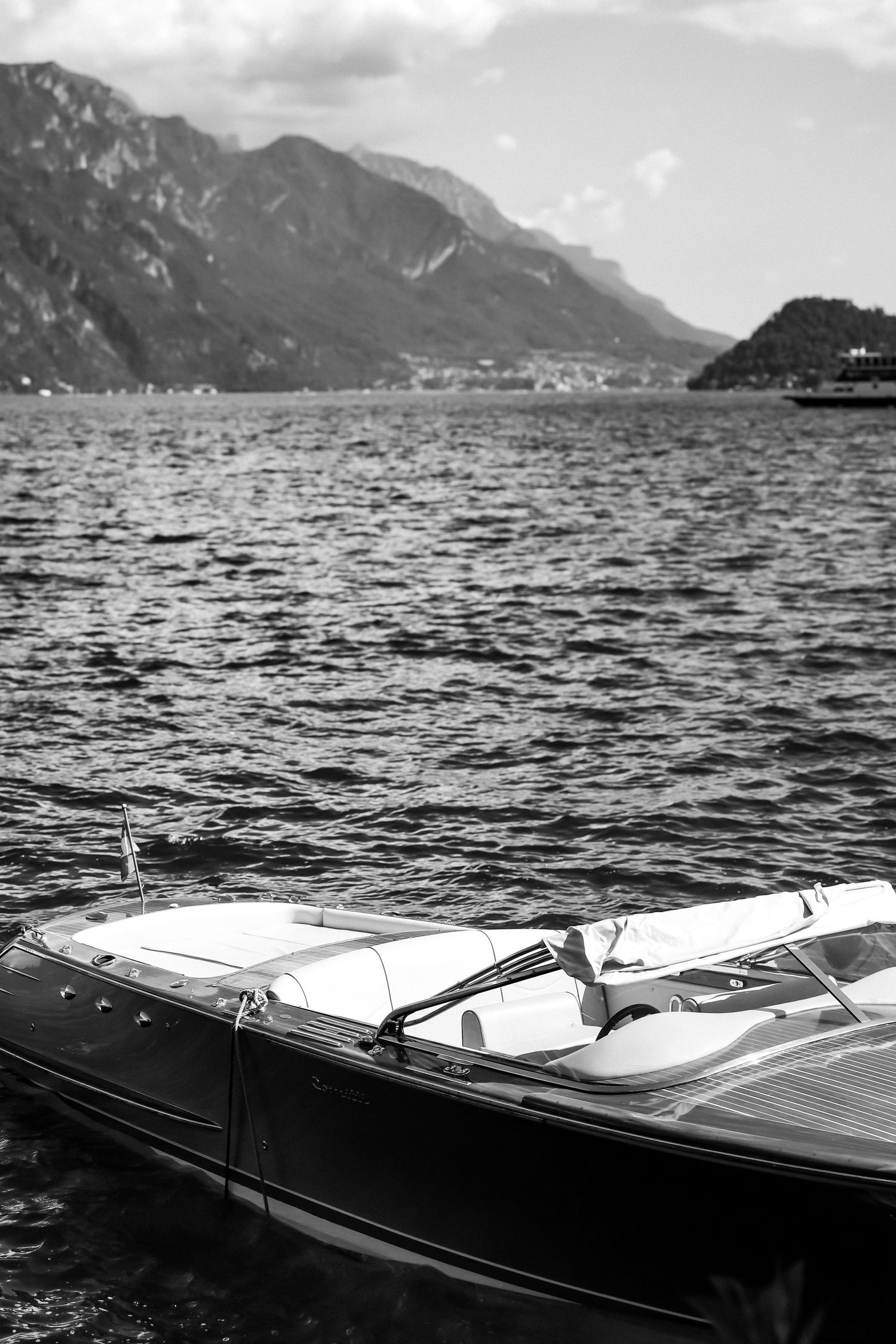 Luxury wooden boat with sleek design moored on a mountain lake with dramatic scenery in the background.