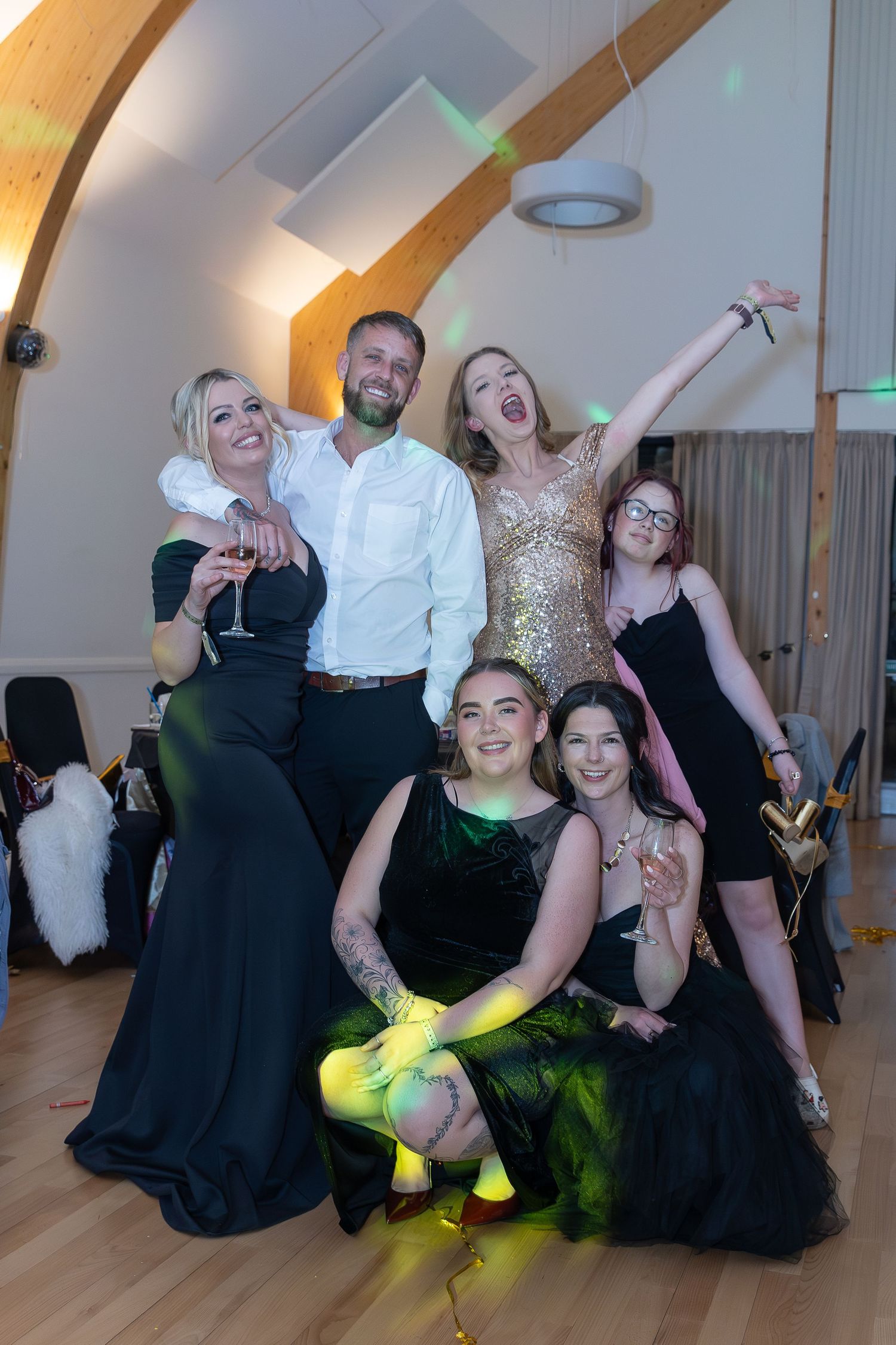 Group of friends posing together at a formal event, wearing elegant black and gold outfits, smiling and celebrating.