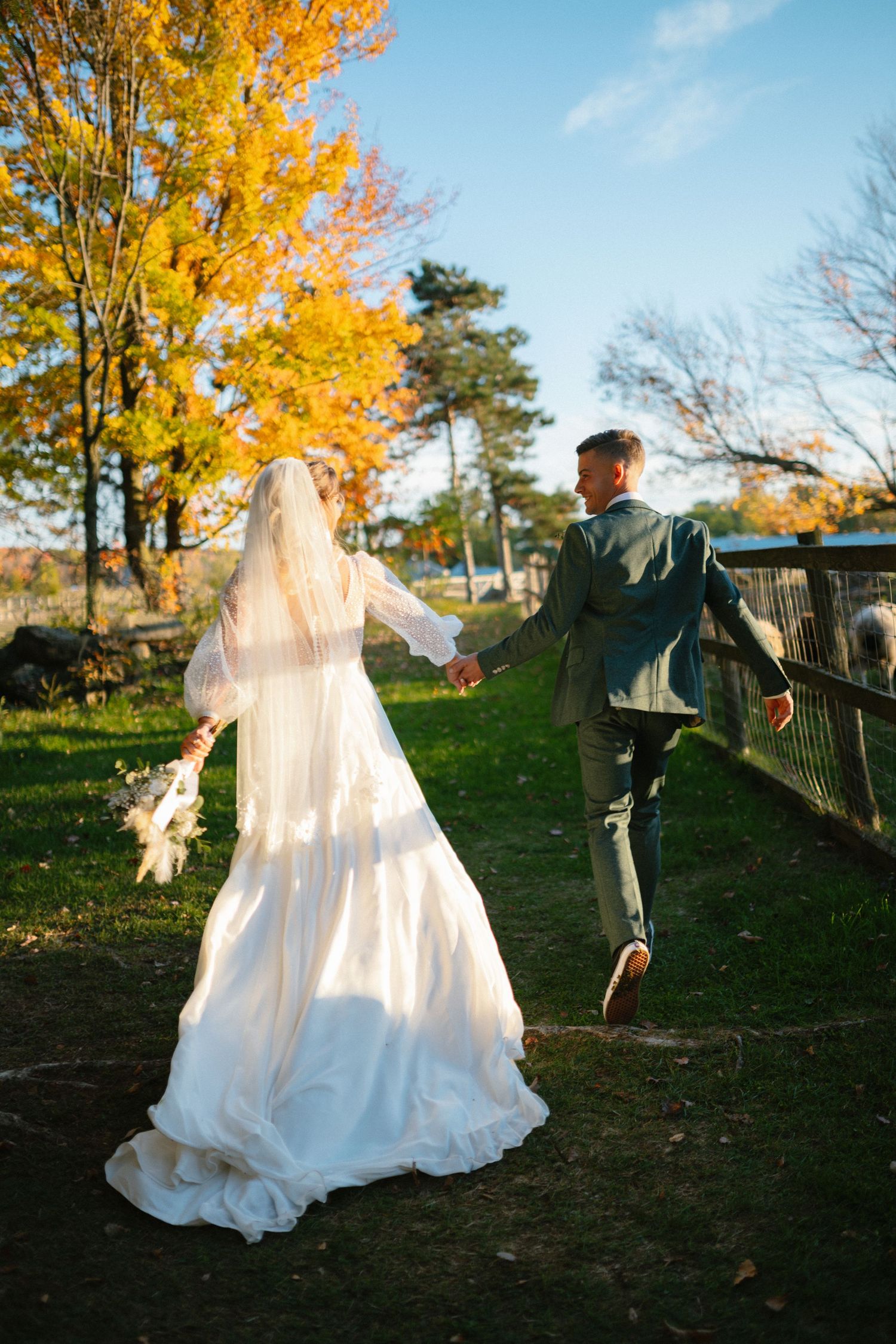 A flowing white wedding dress twirls against autumn trees with vibrant yellow foliage.