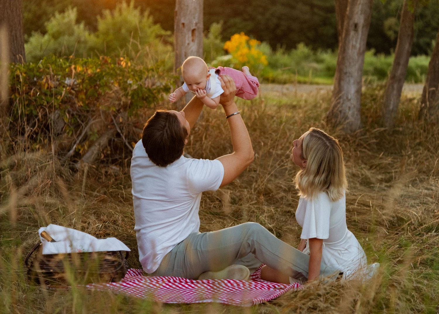 Family enjoying quality time together on a red picnic blanket surrounded by autumn foliage.