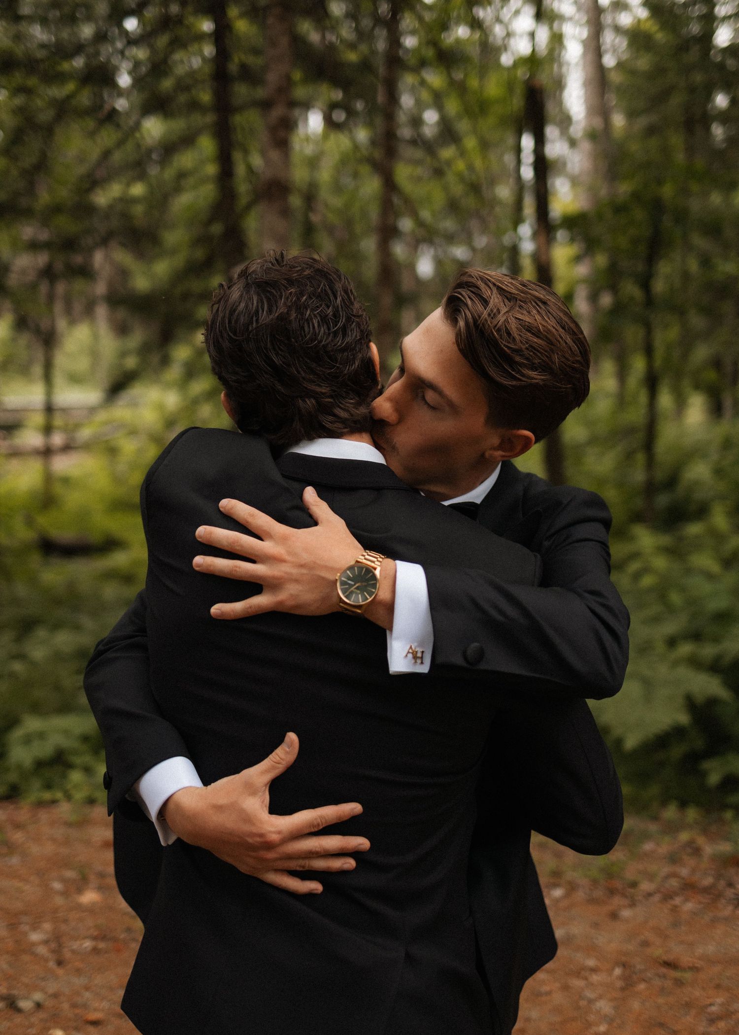 Group embracing in formal suits against a forest backdrop.