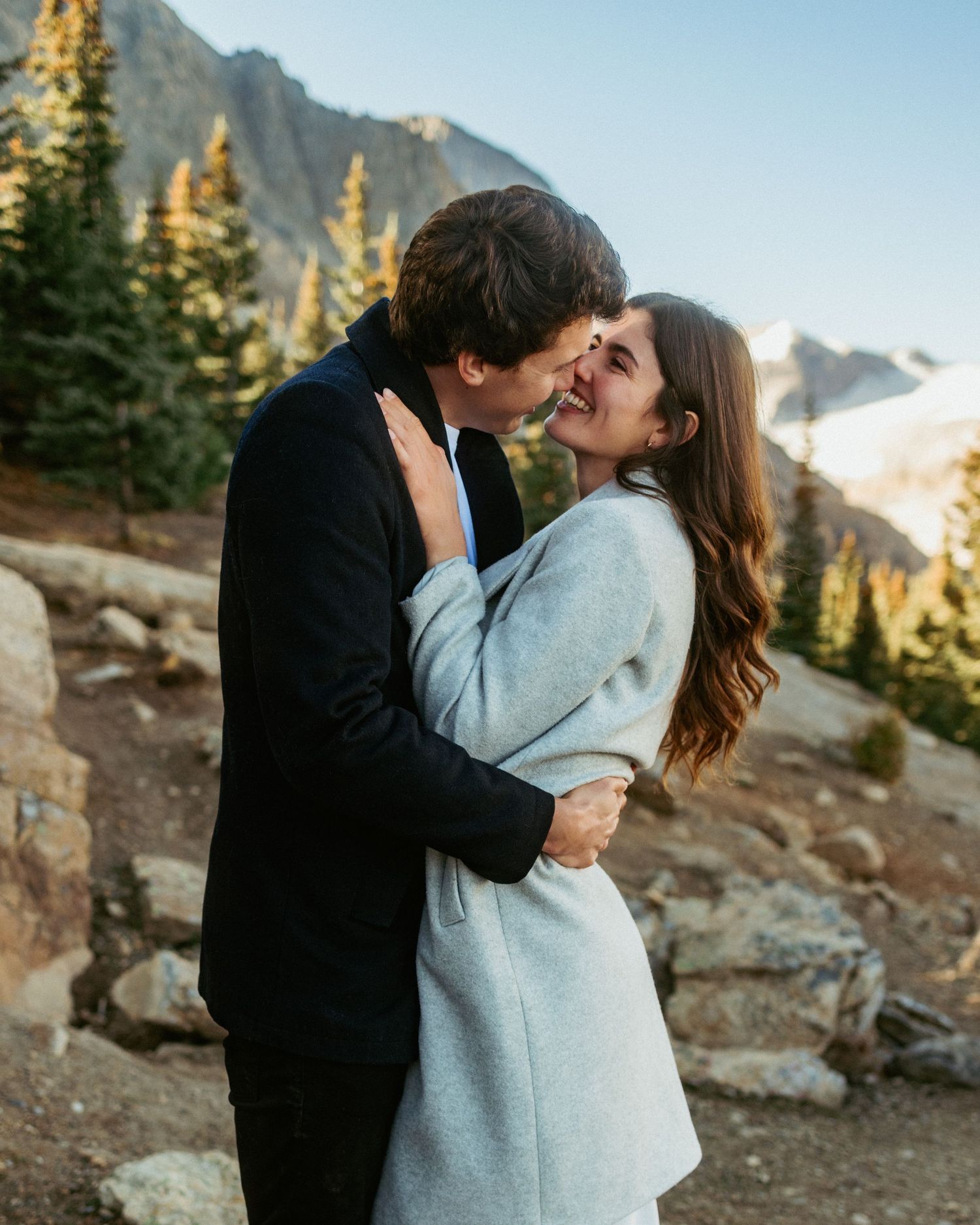 Couple embracing against a scenic mountain backdrop during sunset.