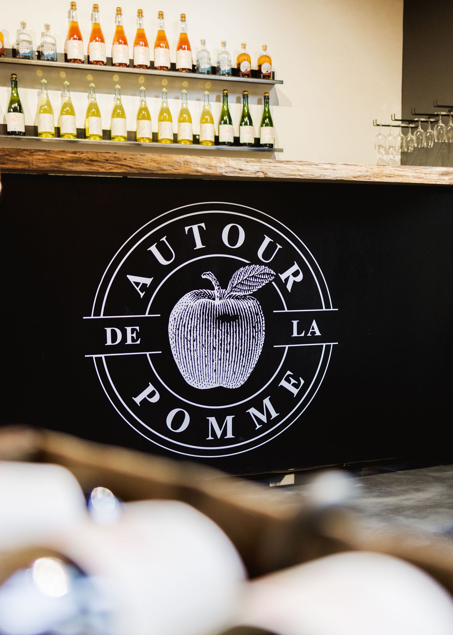 Black signage with apple logo for 'Factory Pomme' displayed in bar setting.