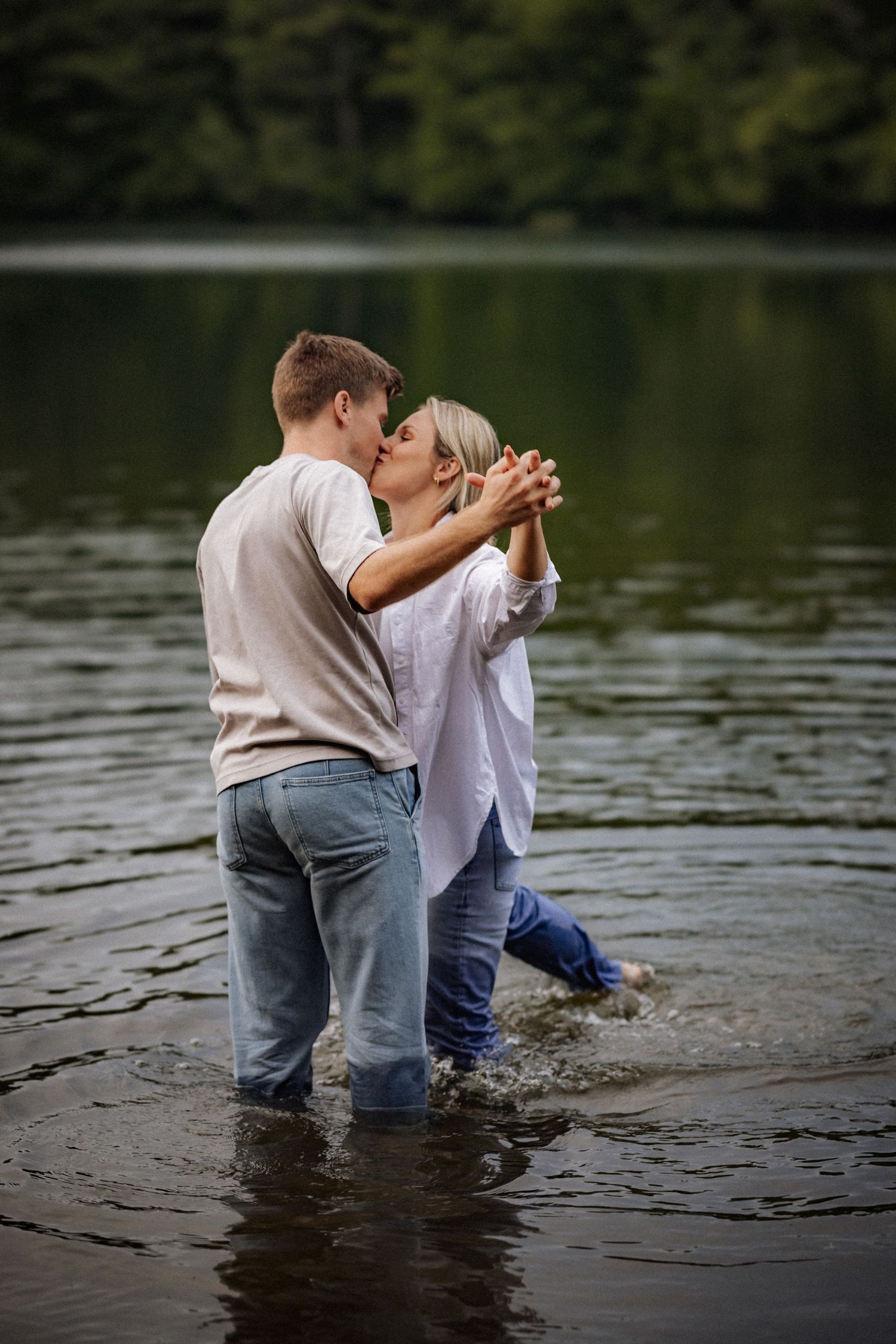 Romantic couple sharing intimate moment while standing in lake water.
