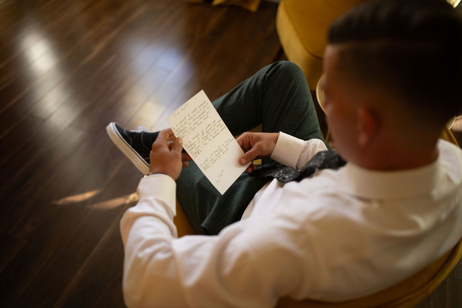 Overhead view of someone in white shirt reading handwritten notes while sitting.