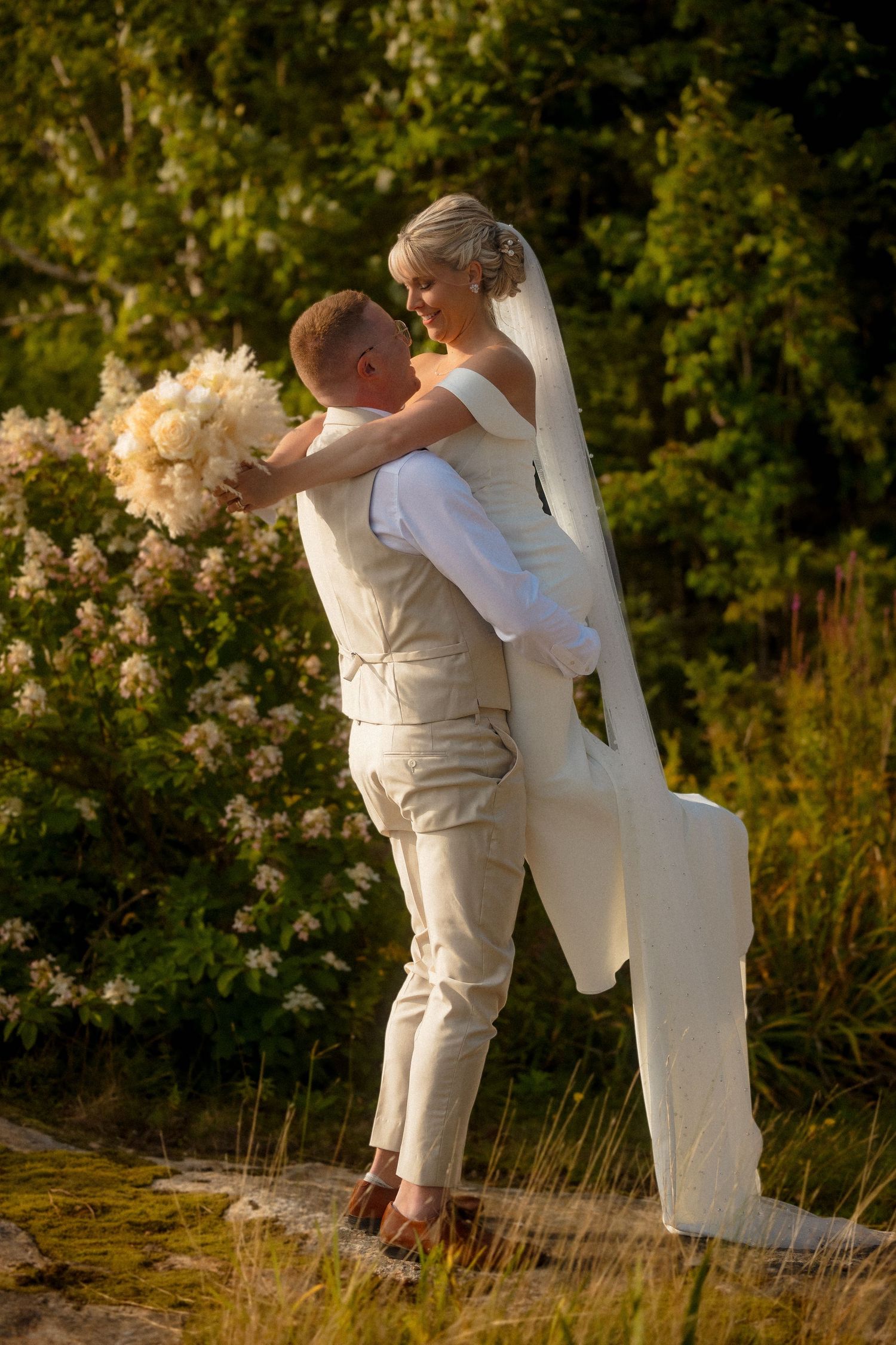 Couple embraces during golden hour photoshoot in a garden with blooming roses.