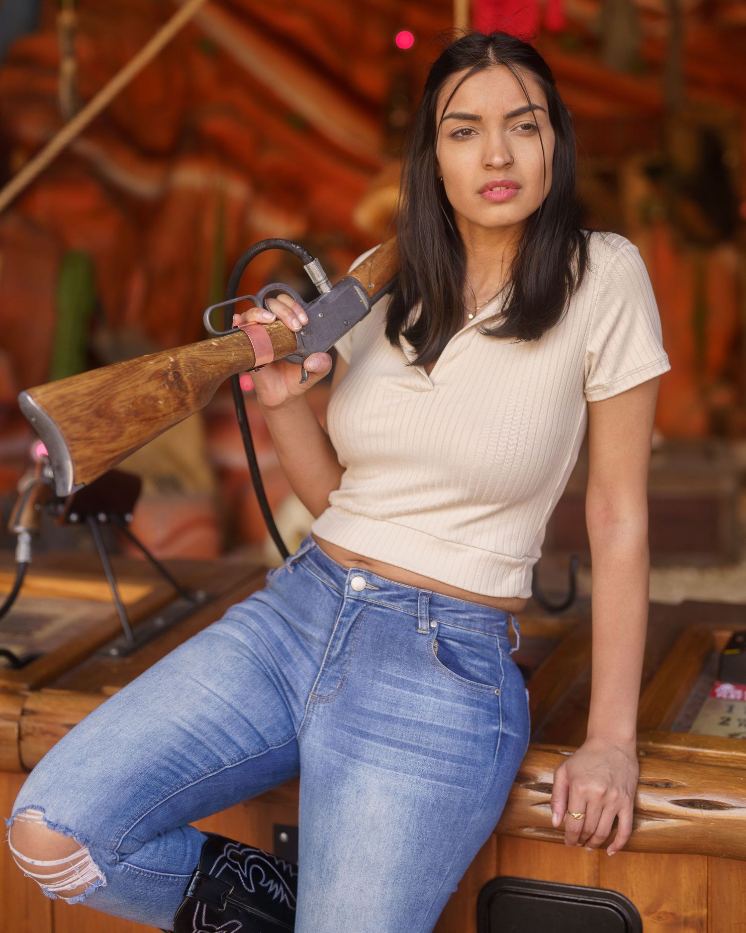 Model in white top and ripped blue jeans poses casually in a rustic setting.
