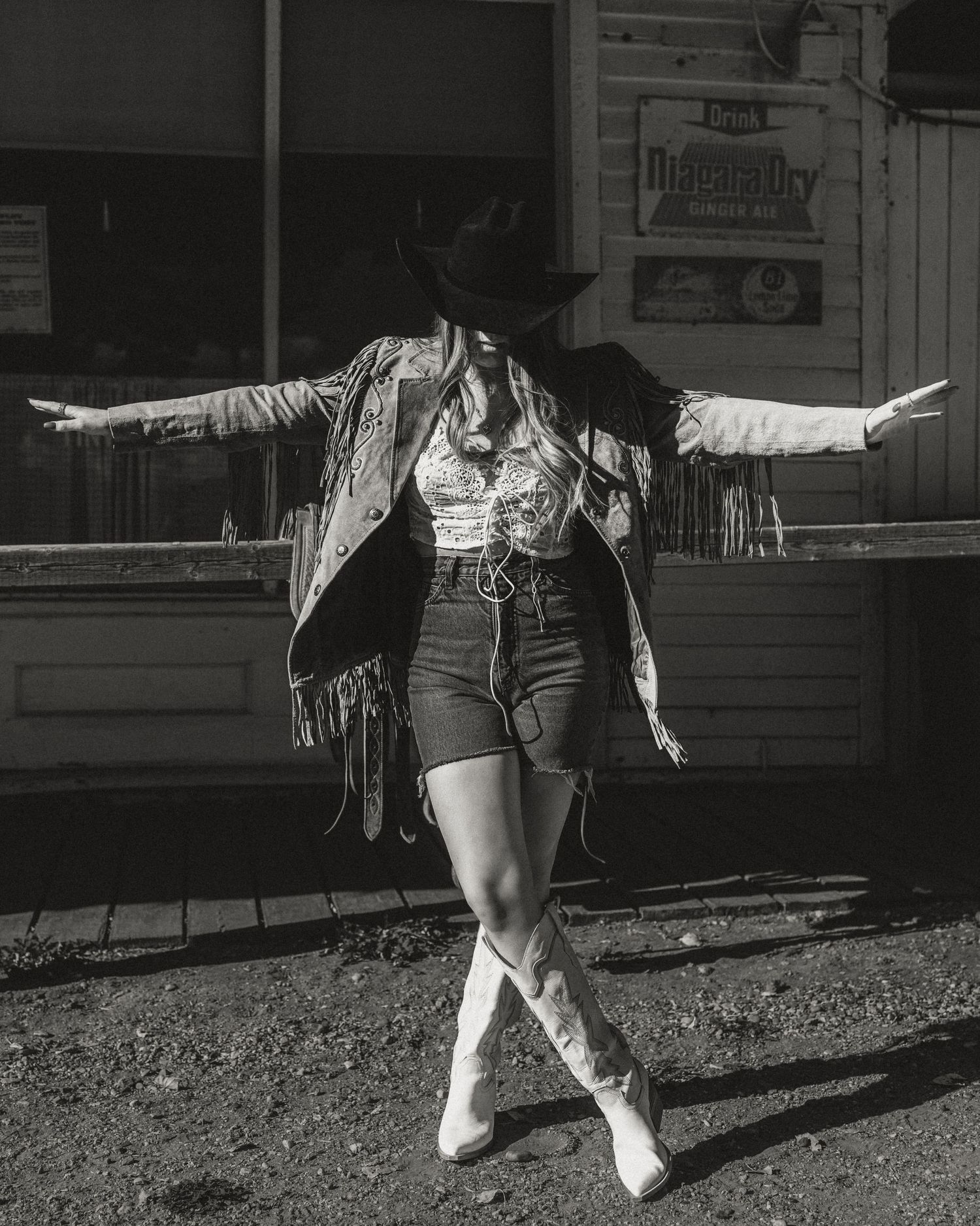 Black and white photo of someone walking along railroad tracks with arms outstretched in a playful pose.