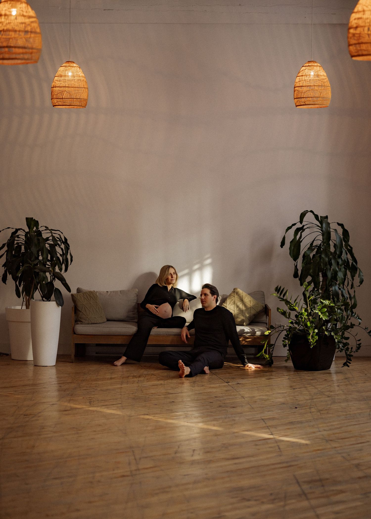 Minimalist studio space with pendant lights and indoor plants along a wall.