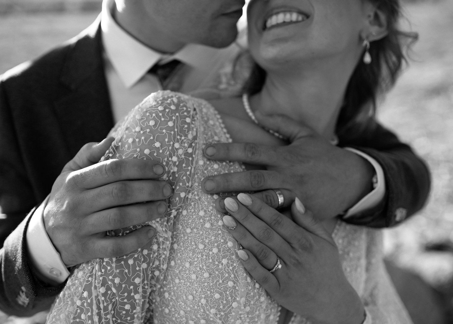 Intimate black and white photo showing hands embracing in sparkly wedding attire.
