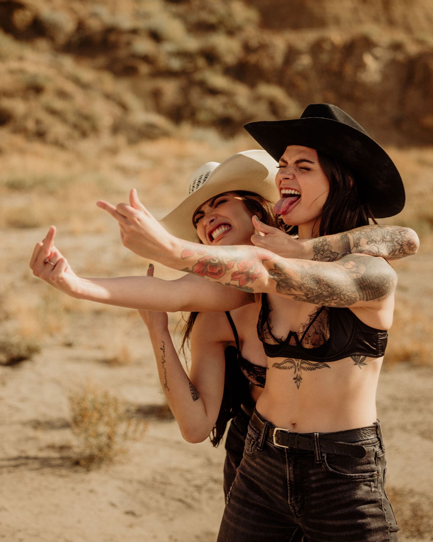 Two people laugh and dance together joyfully in a desert setting with warm golden lighting.