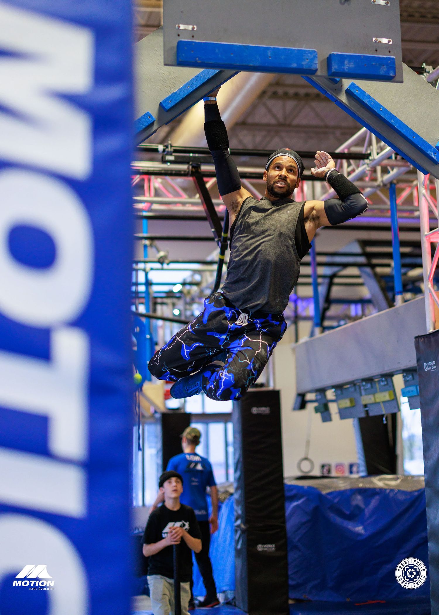 Athletes performing advanced calisthenics moves on blue gym equipment.