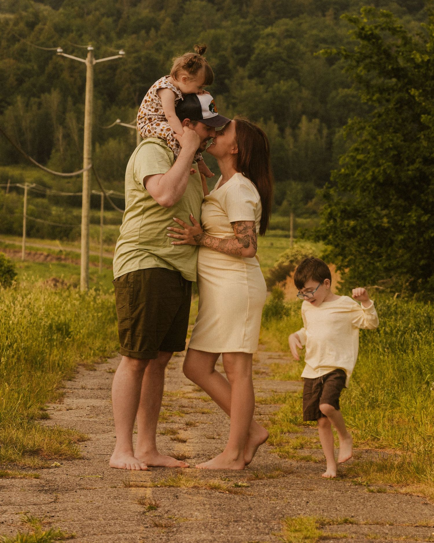 Family playing and embracing on dirt path with mountain scenery.