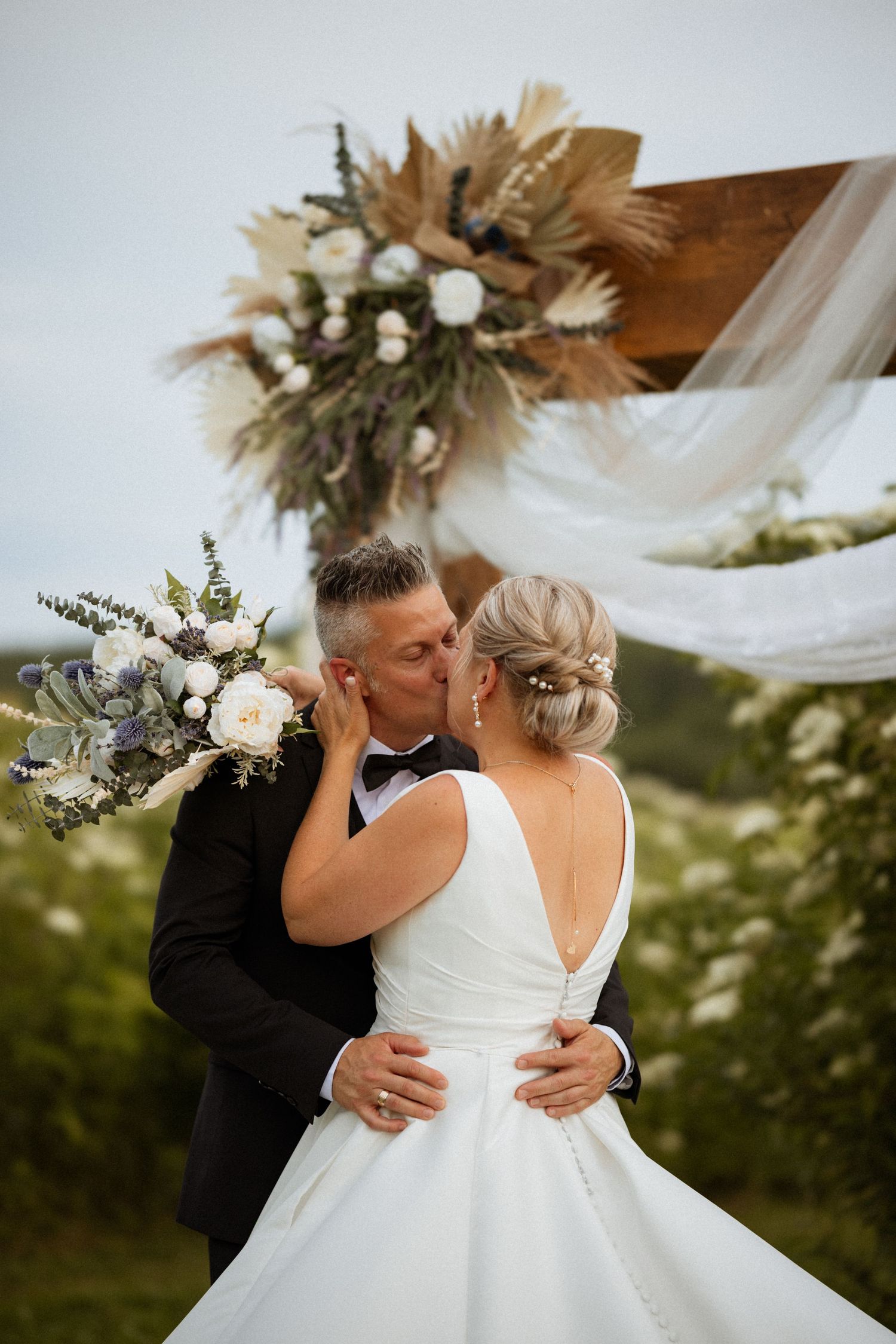 Bride and groom share an intimate moment against natural backdrop with dried flower decor.