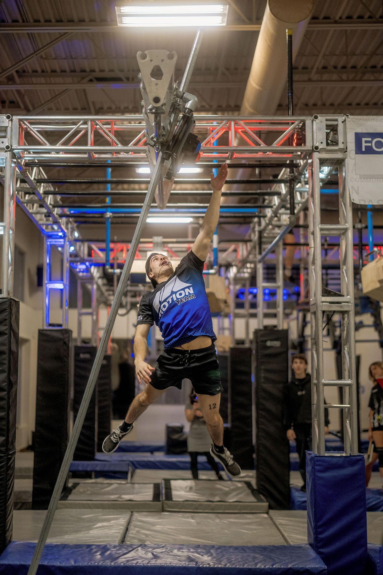 Person performing acrobatic moves on suspended bars in a gym setting.