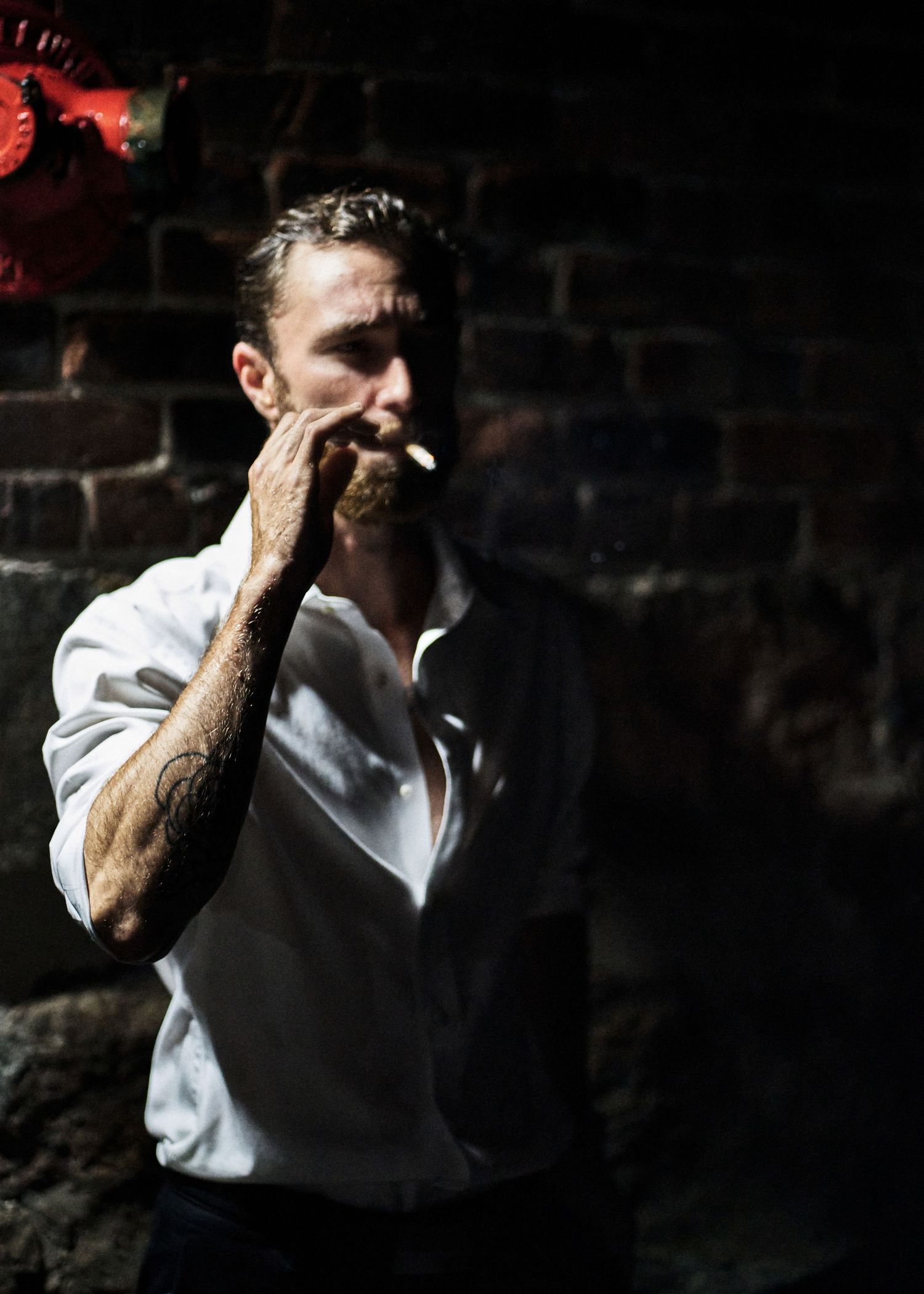 Dramatic portrait of person in white shirt against dark background.
