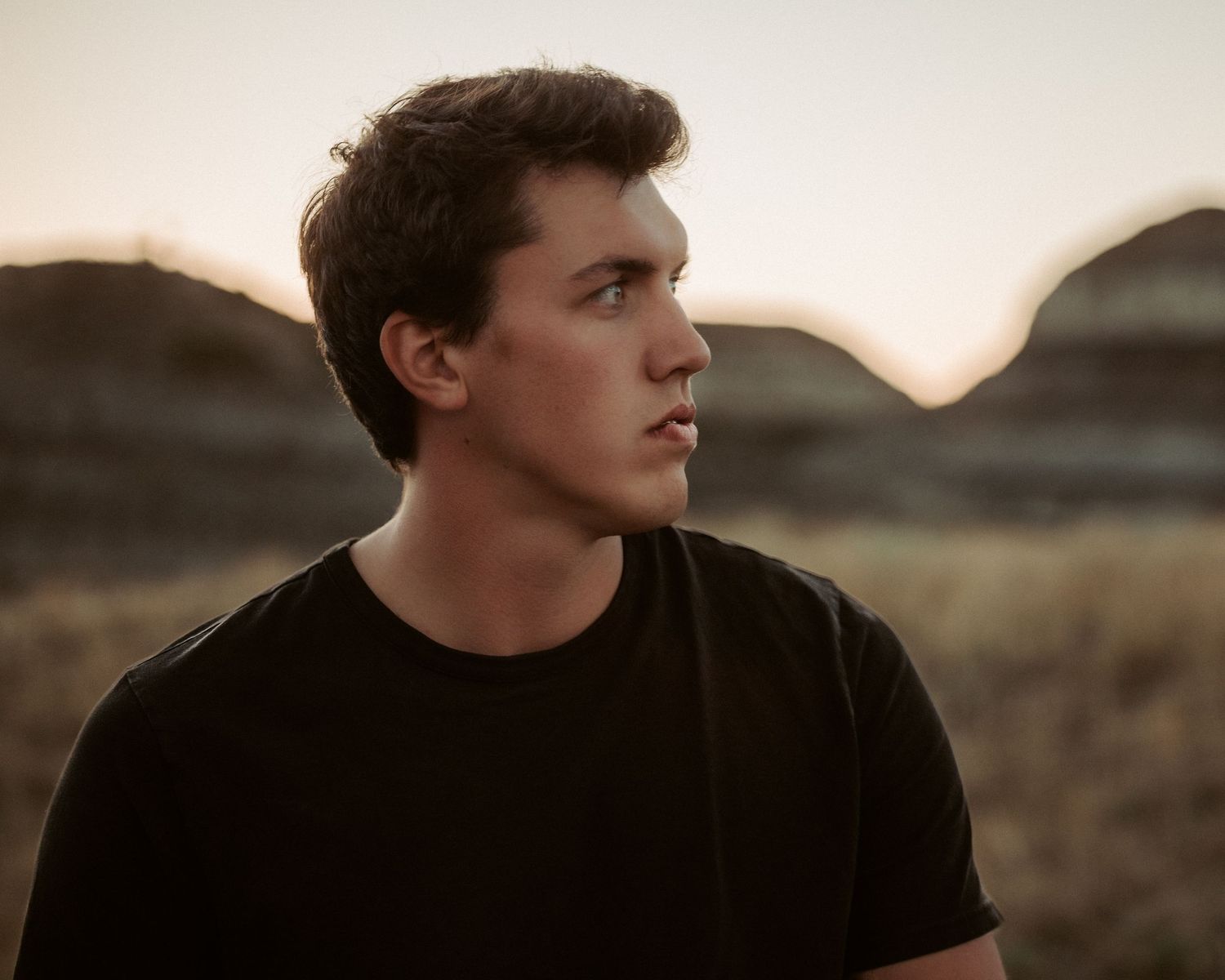 Profile view of person in dark clothing against sunset sky.