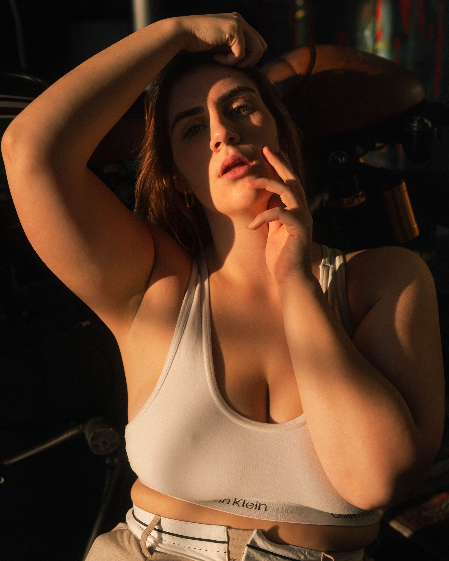 Athletic figure in white sports bra poses in dramatic lighting.
