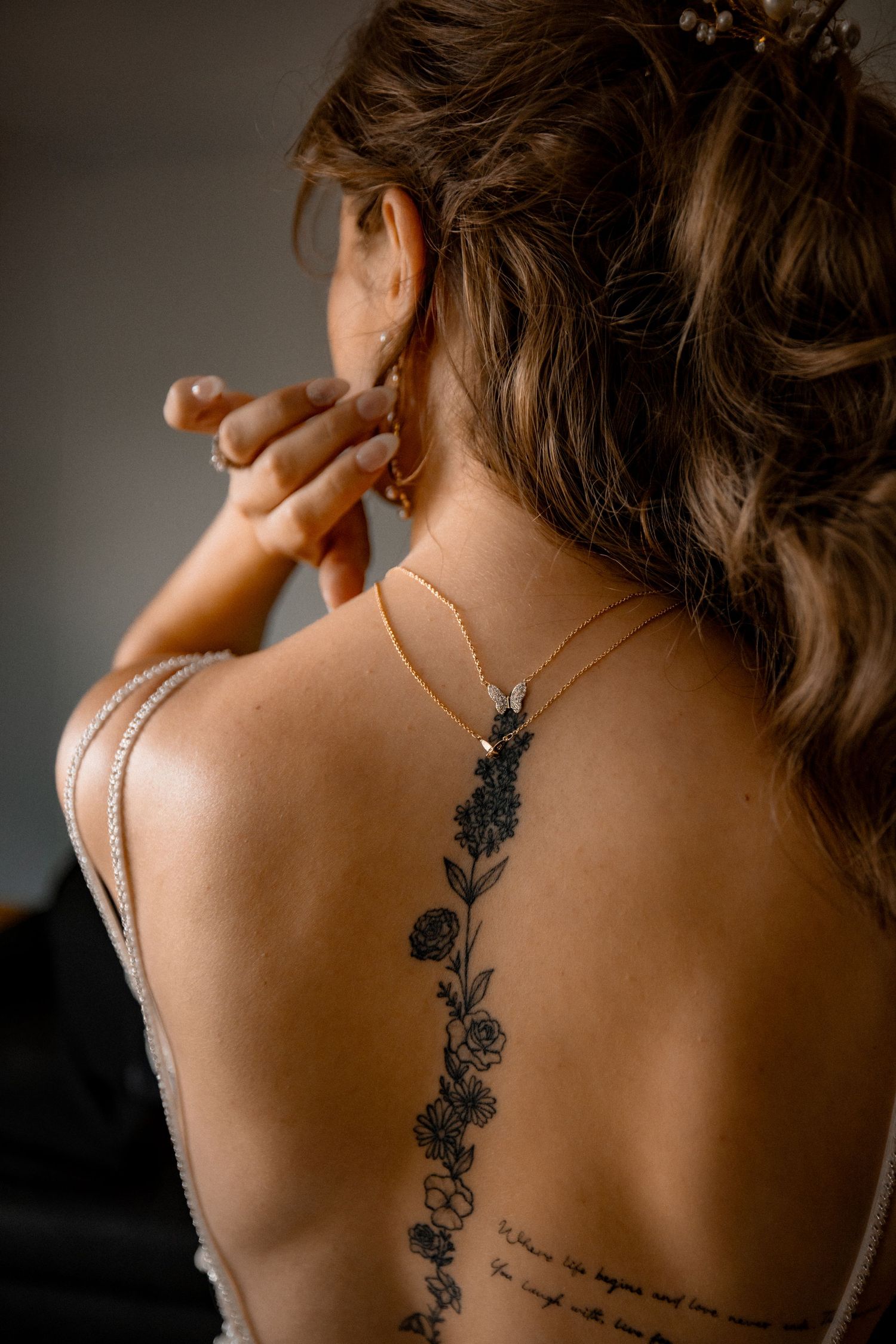 Floral tattoo design on a person's back with delicate black ink linework.