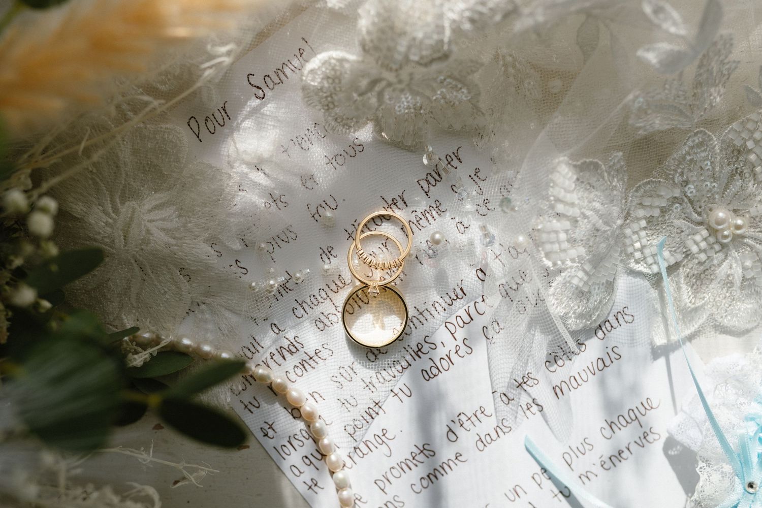 Two wedding rings placed on handwritten paper with delicate lace details.