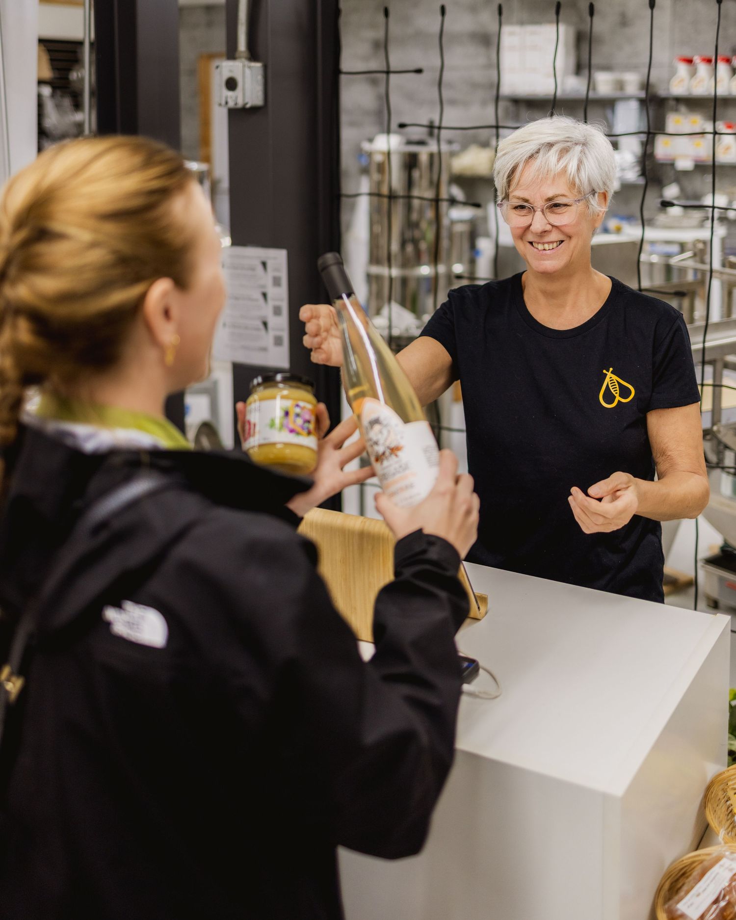 Staff member serving customers at counter during tasting event.