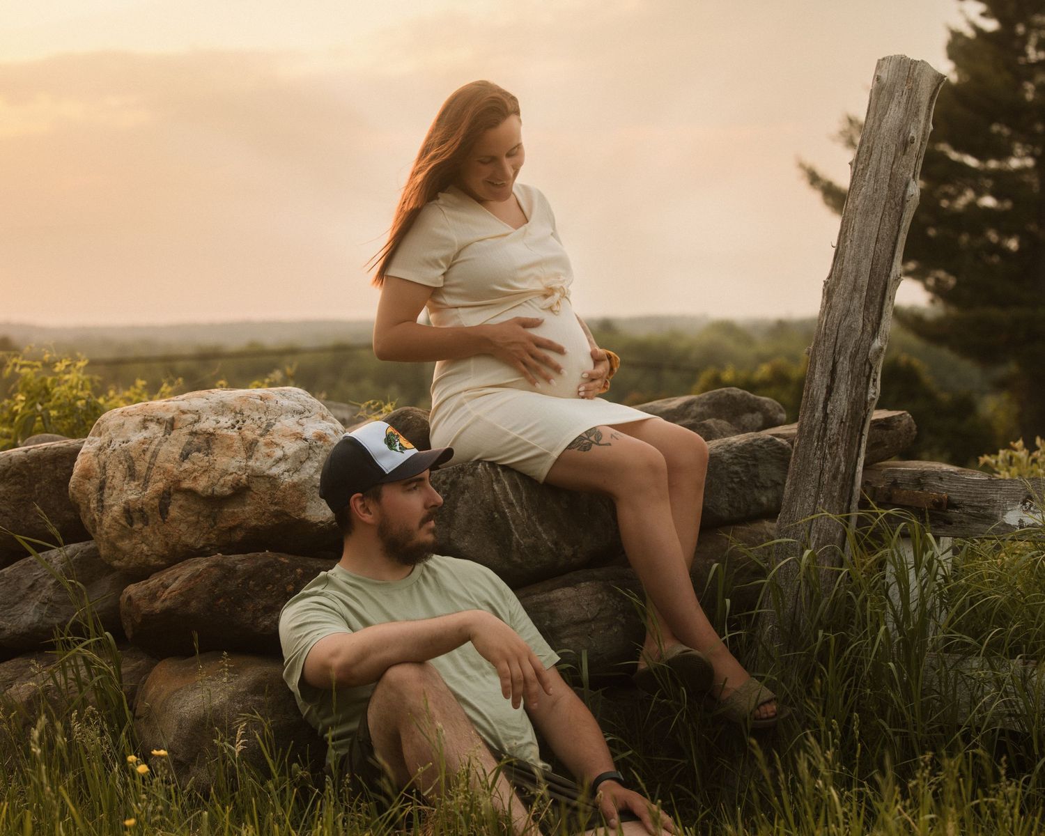 Family relaxing on rocky outcrop during golden hour photo session.