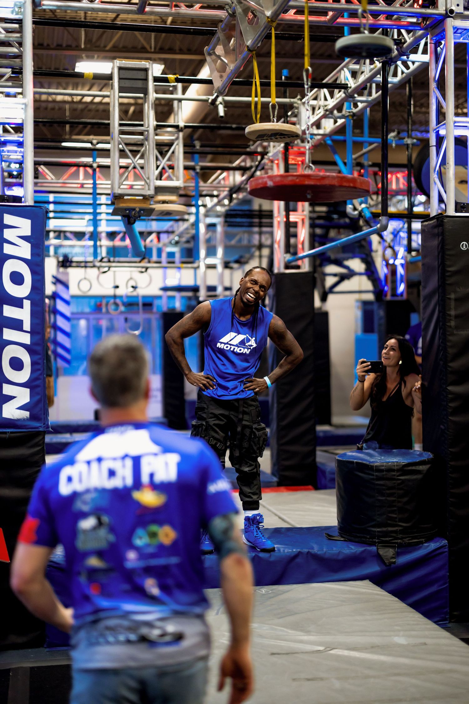 Athletes training at an indoor gym facility with blue equipment and lighting.