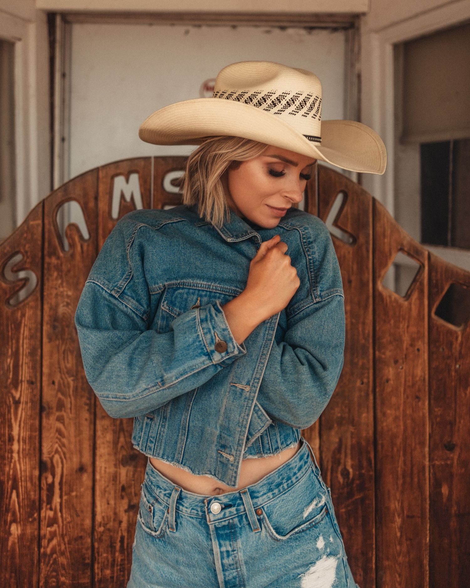 Western-themed fashion shoot with denim jacket against vintage wooden fence.