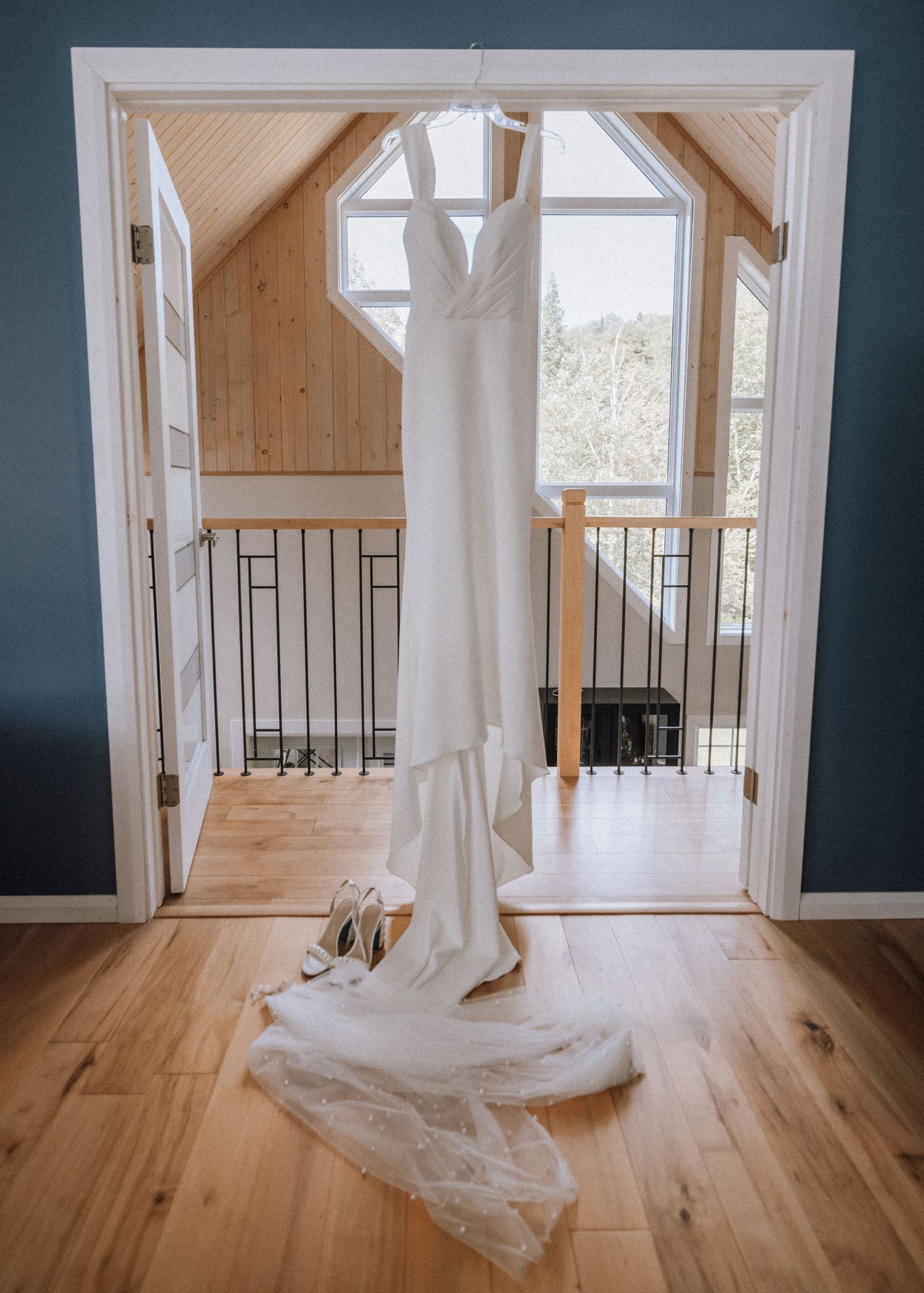 White wedding veil flowing across light hardwood floor in elegant interior space with navy walls.