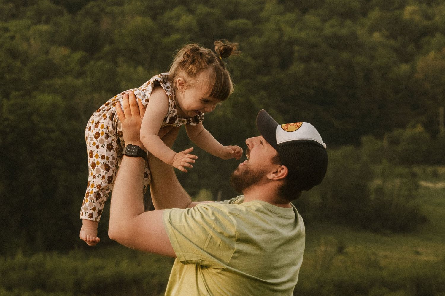 Couple embracing in a romantic moment against green mountain backdrop.
