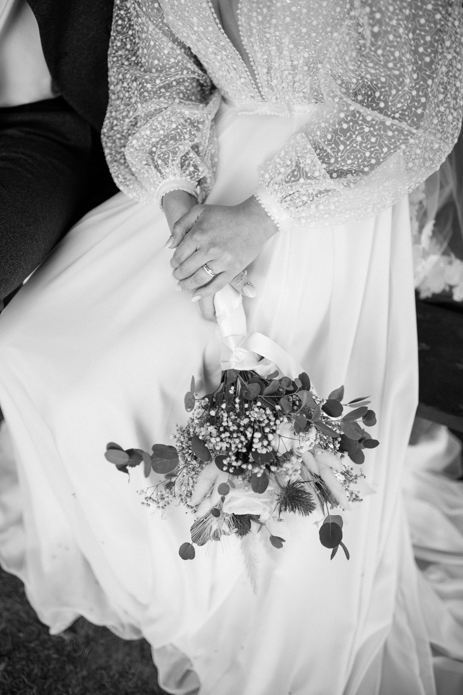 Wedding dress details with sparkles and floral decorations against a white flowing gown.