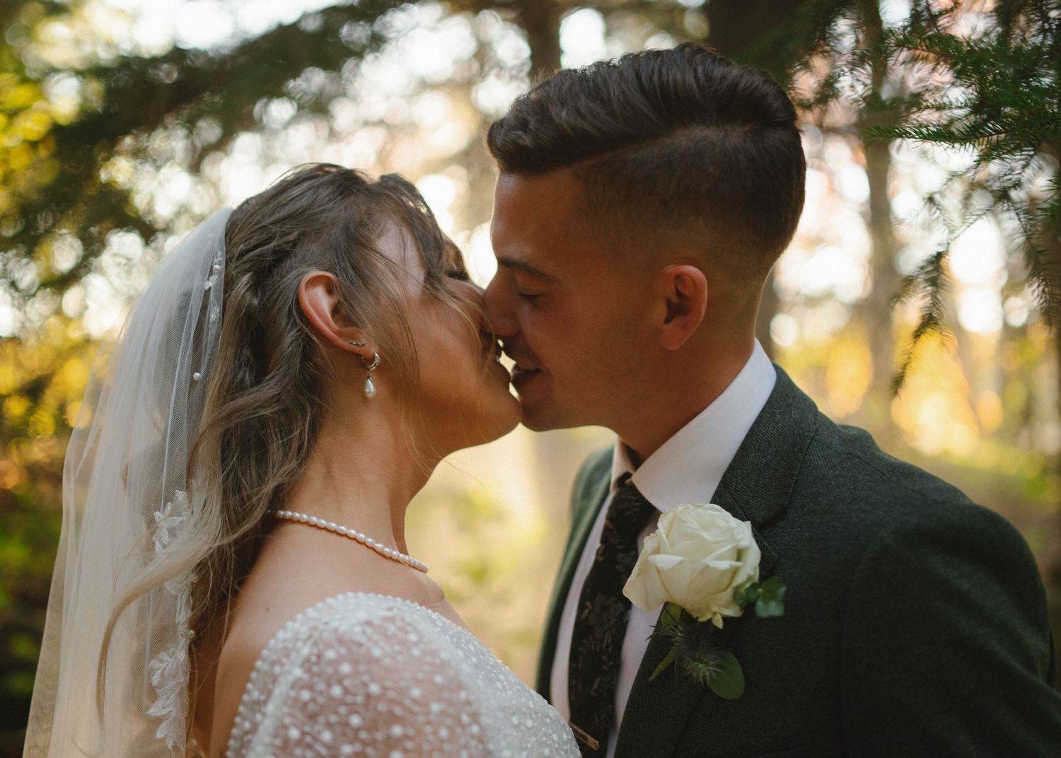 Intimate wedding portrait with warm sunset lighting filtering through trees.