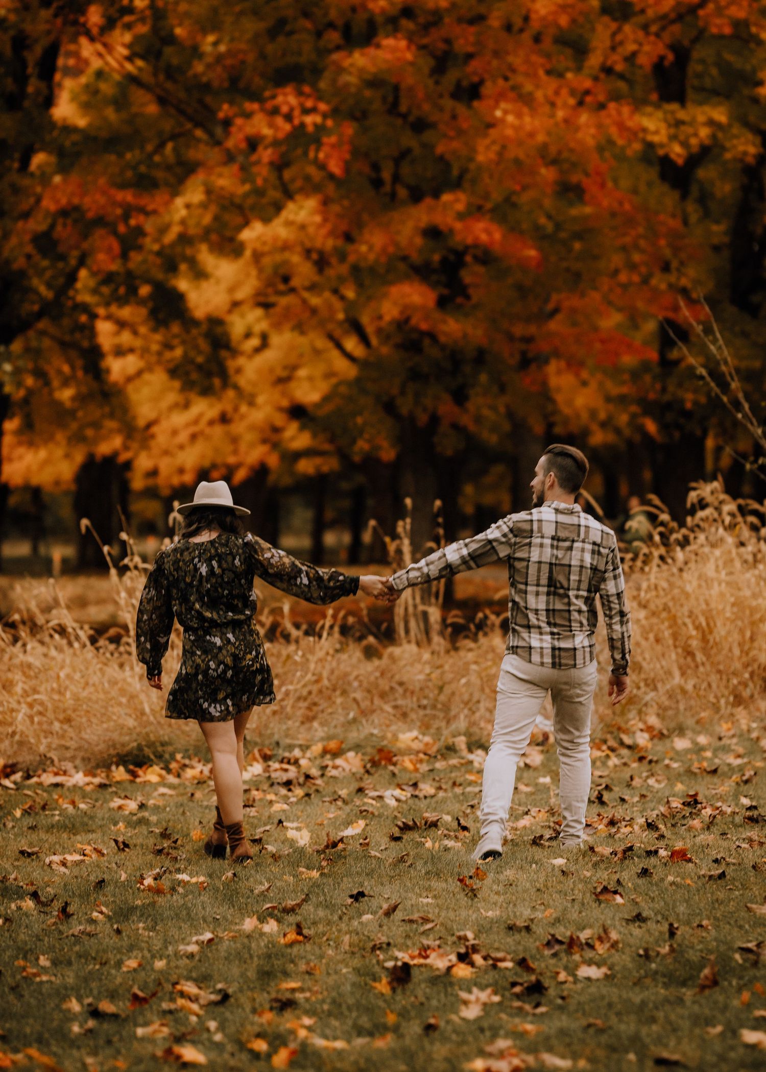 Family walking through autumn foliage with orange and golden trees in the background.