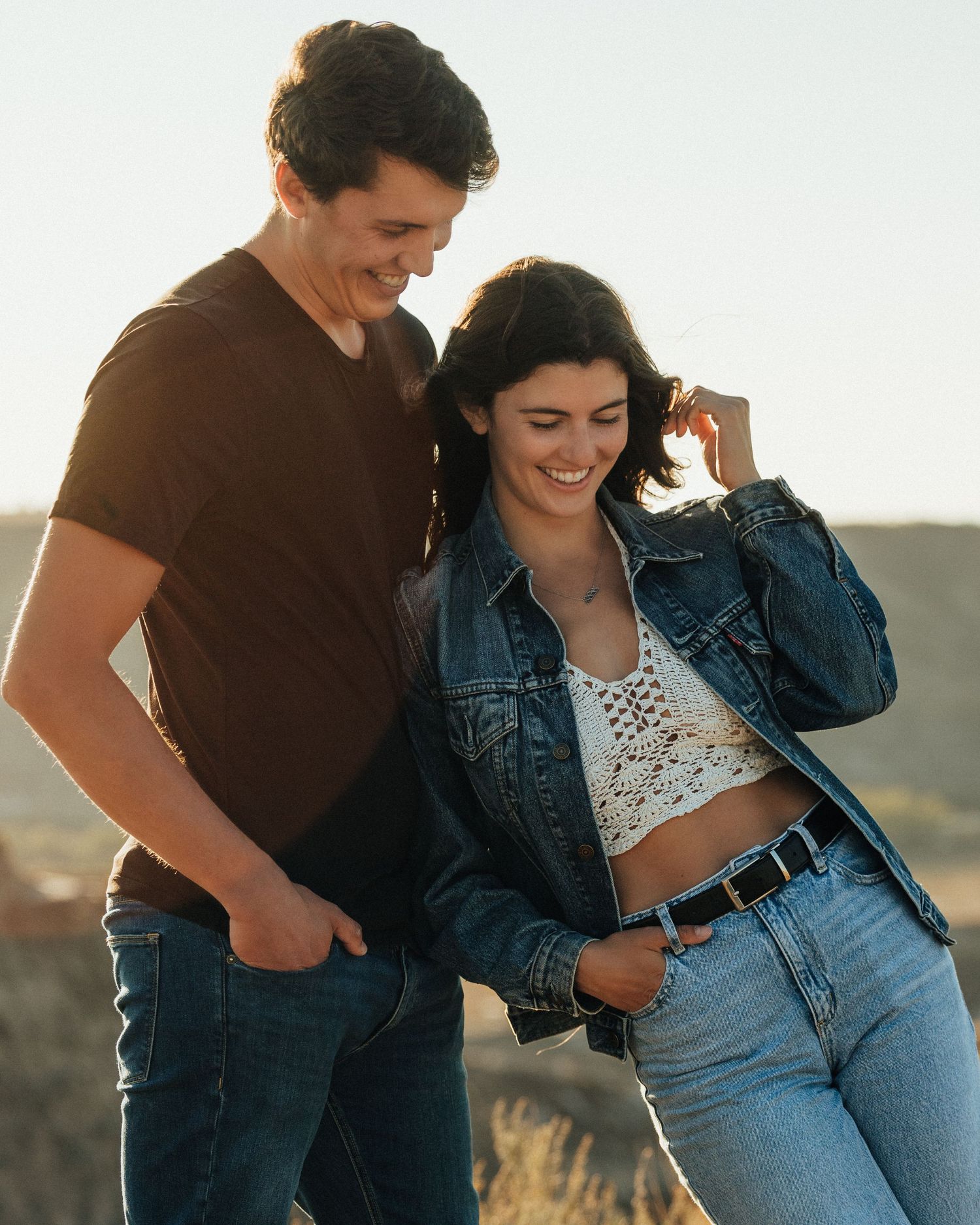 Couple in matching casual wear laughing together in natural setting.