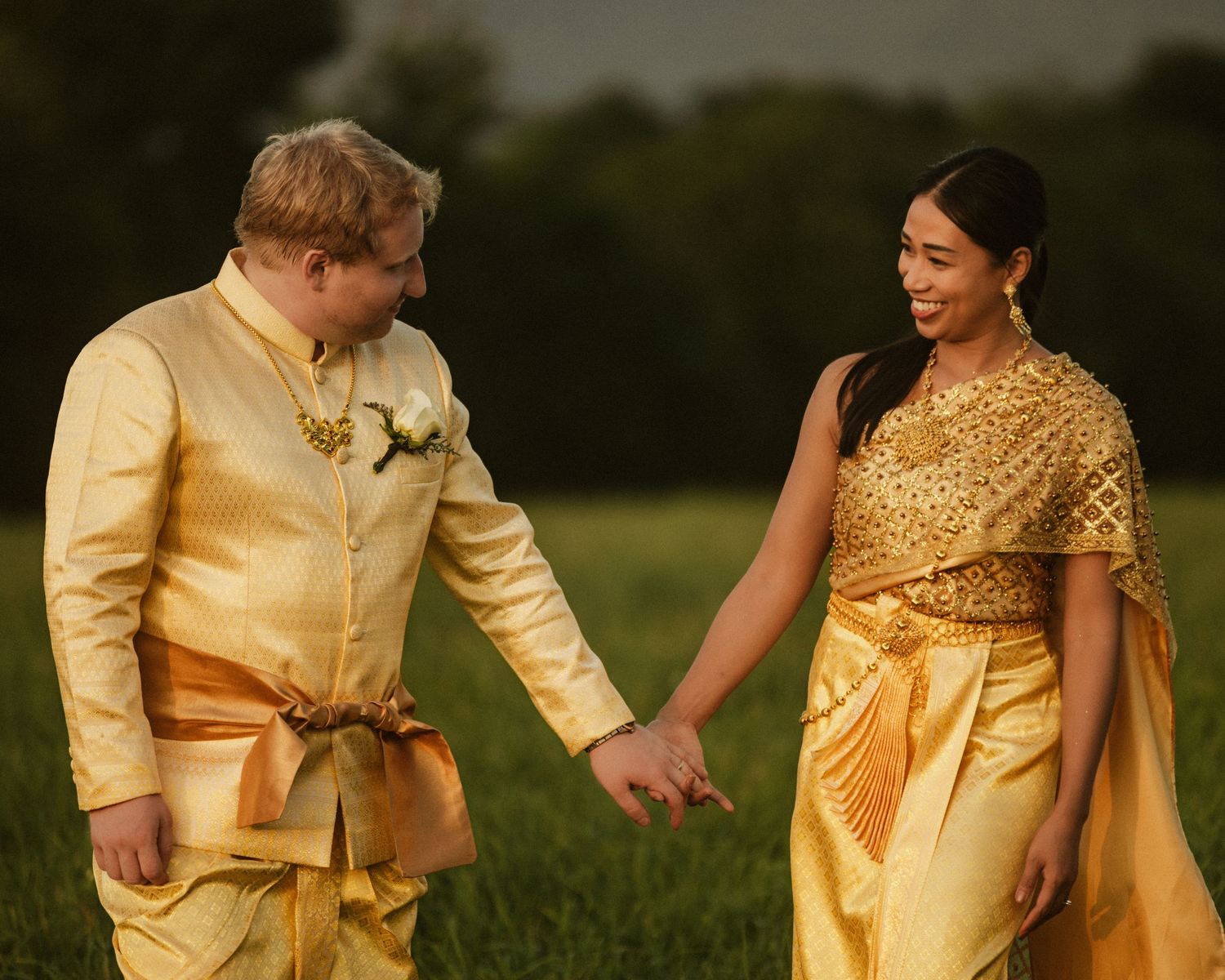 Couple in matching yellow formal attire share romantic moments in a field.