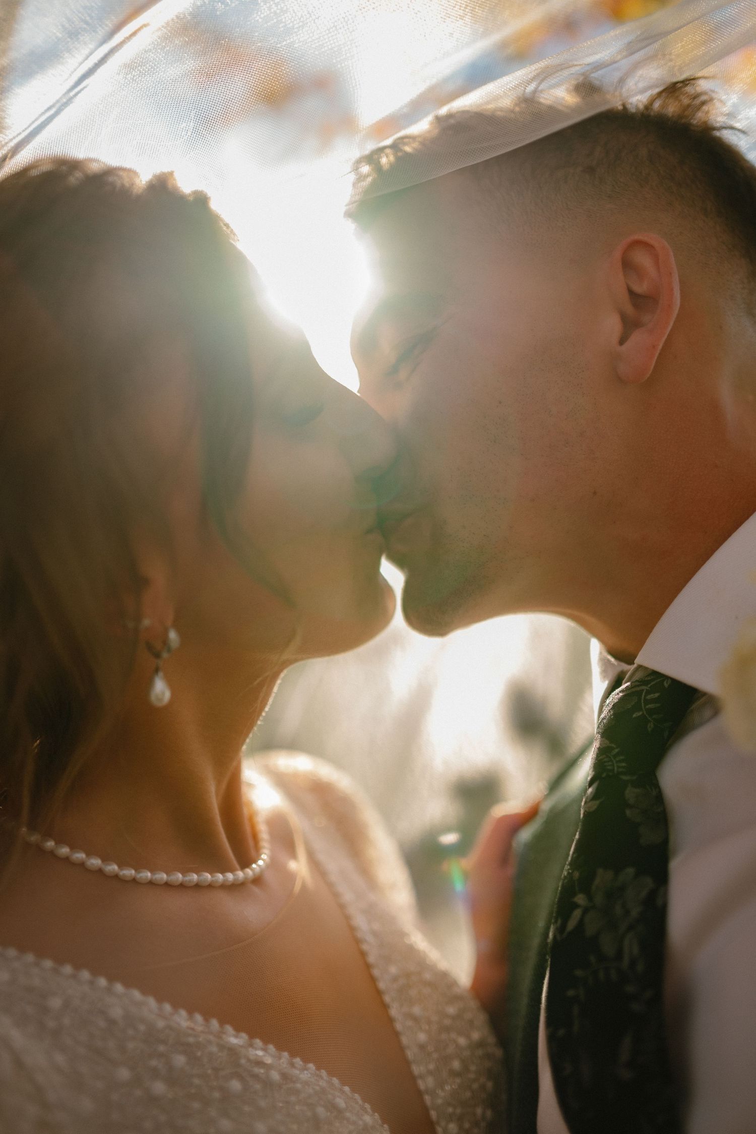 Sunlit close-up of couple with pearl necklace detail.