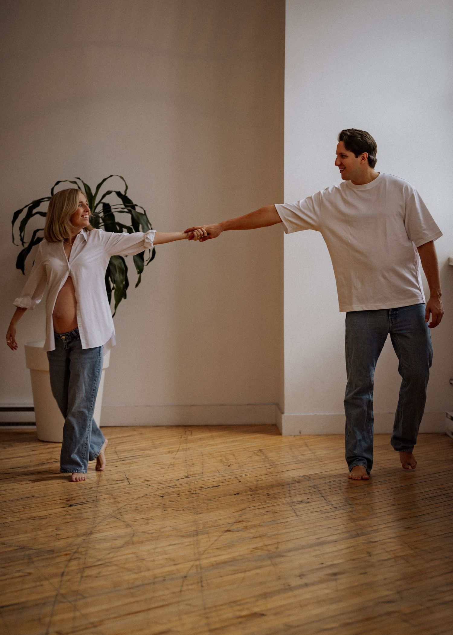 A playful maternity photo sequence showing movement across a wooden floor.