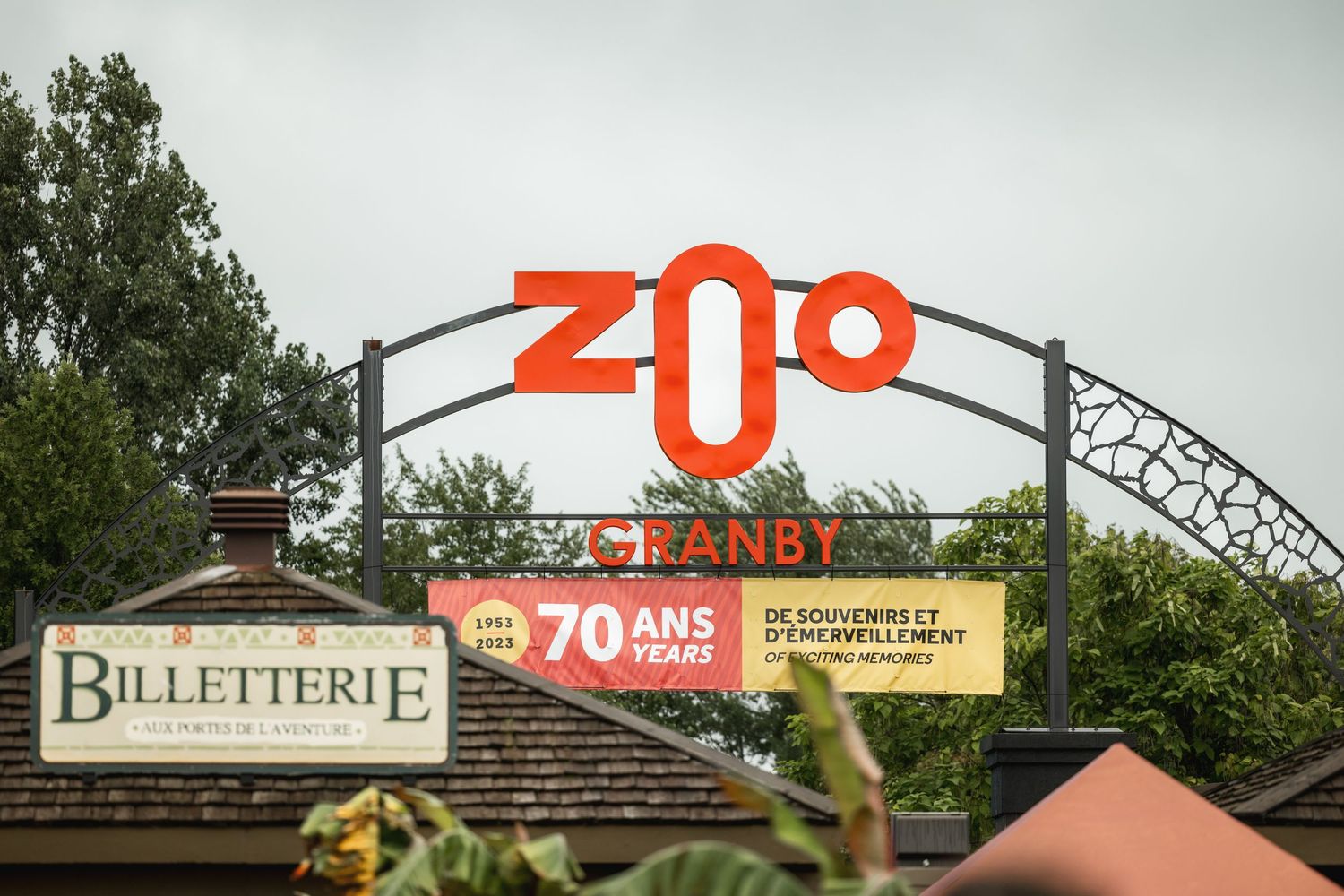 Zoo entrance sign with decorative arch and ticket booth visible.