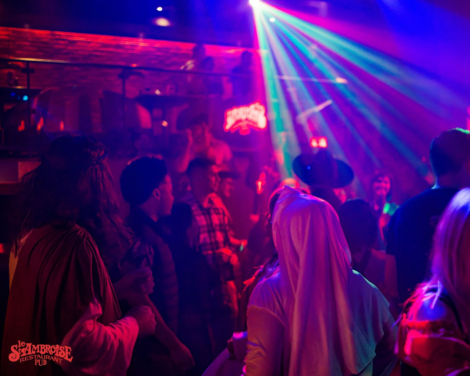 Nightclub dance floor illuminated with colorful laser lights and blue ambiance.
