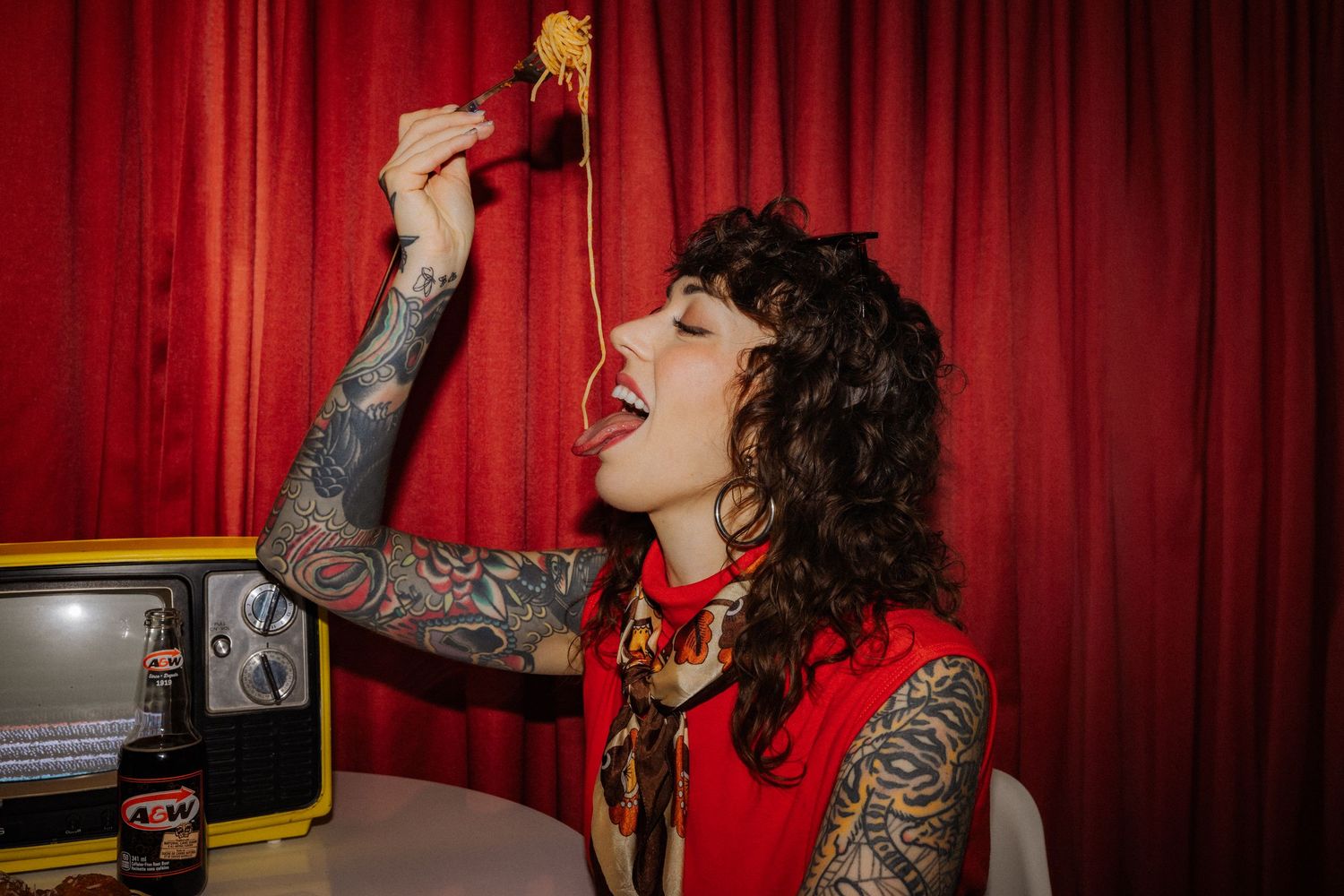 Performer in front of red curtain backdrop with dramatic lighting and gestures.