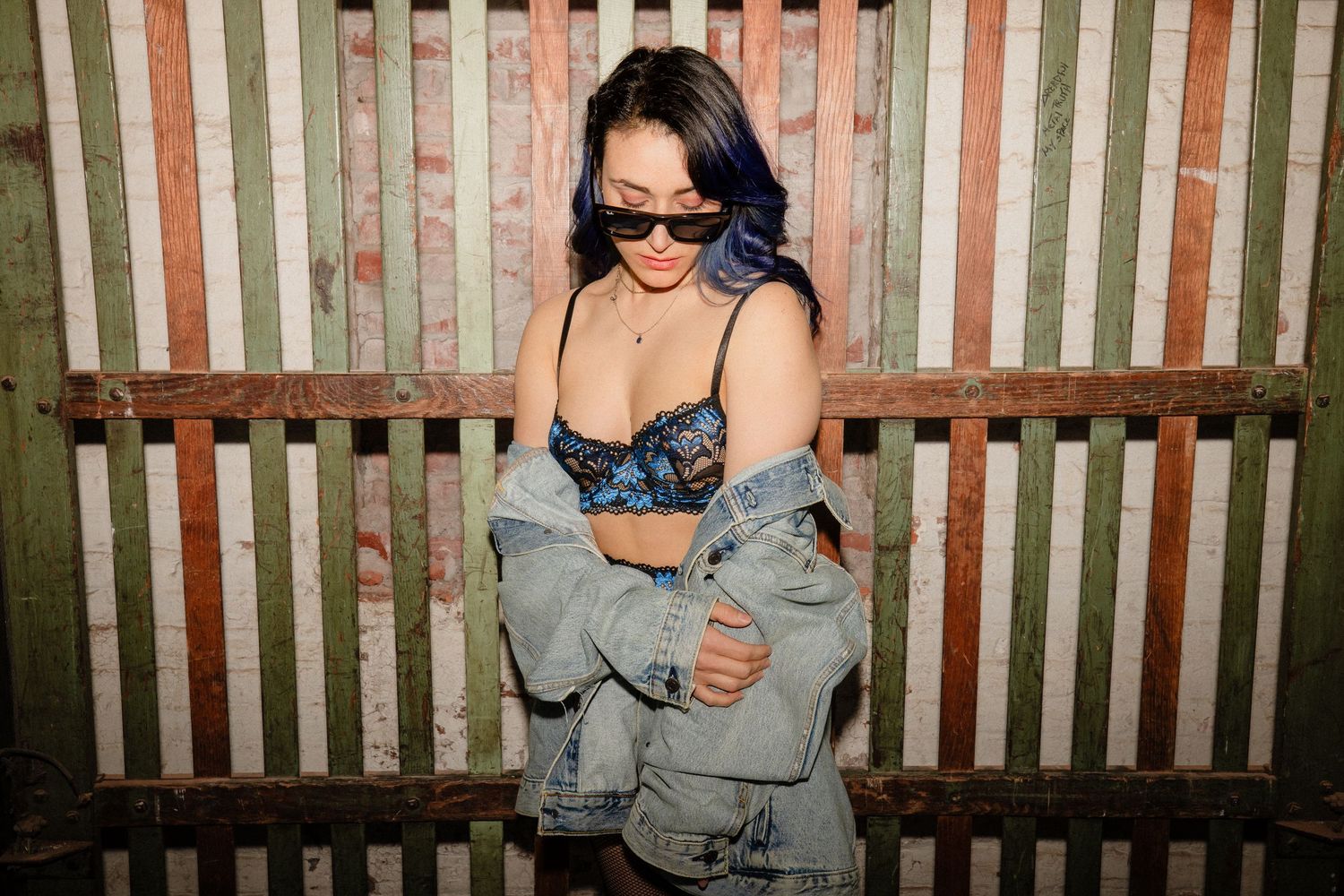 Artistic sequence of poses against striped fence background in casual denim style.