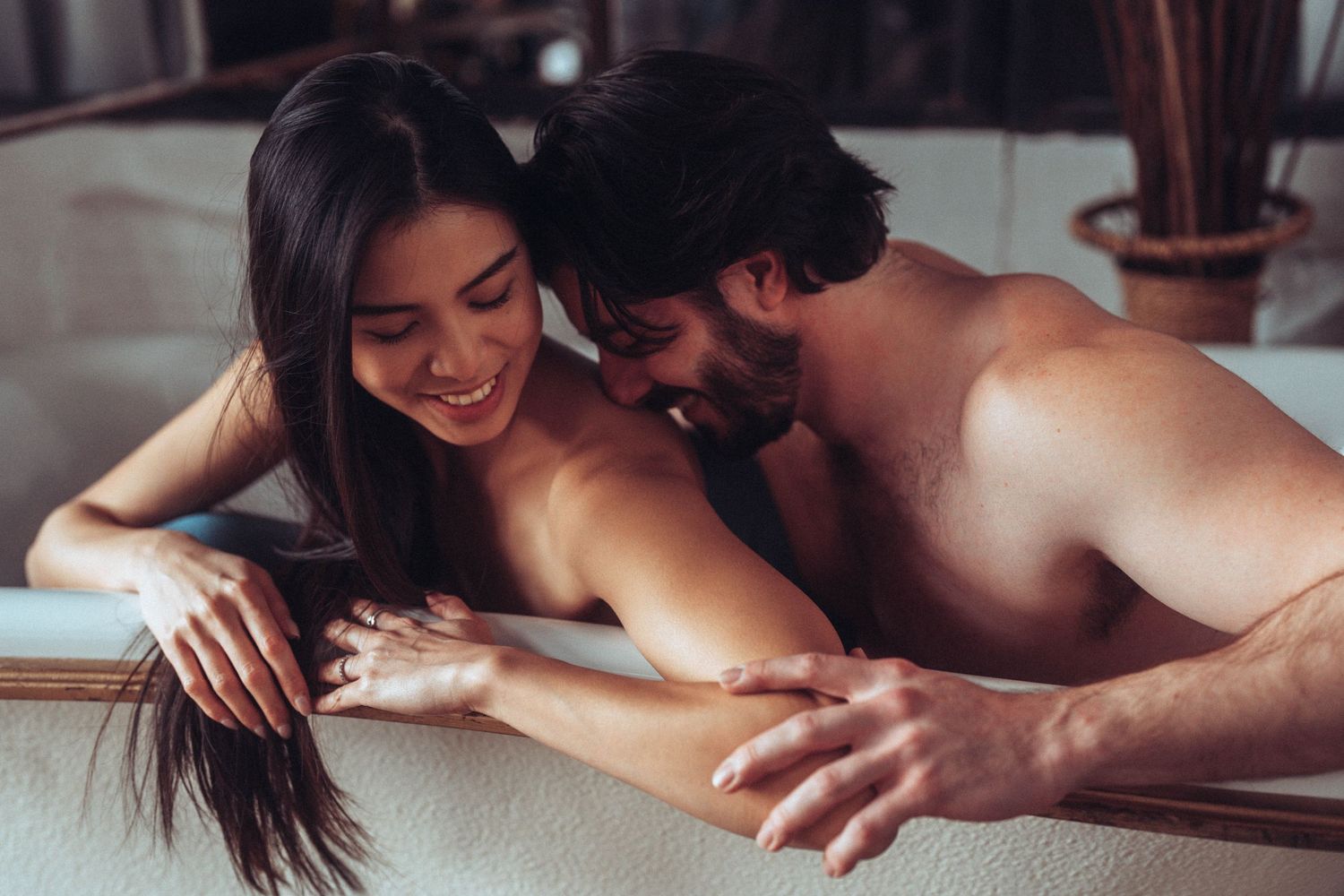 Intimate couple sharing a tender moment together on white sheets.