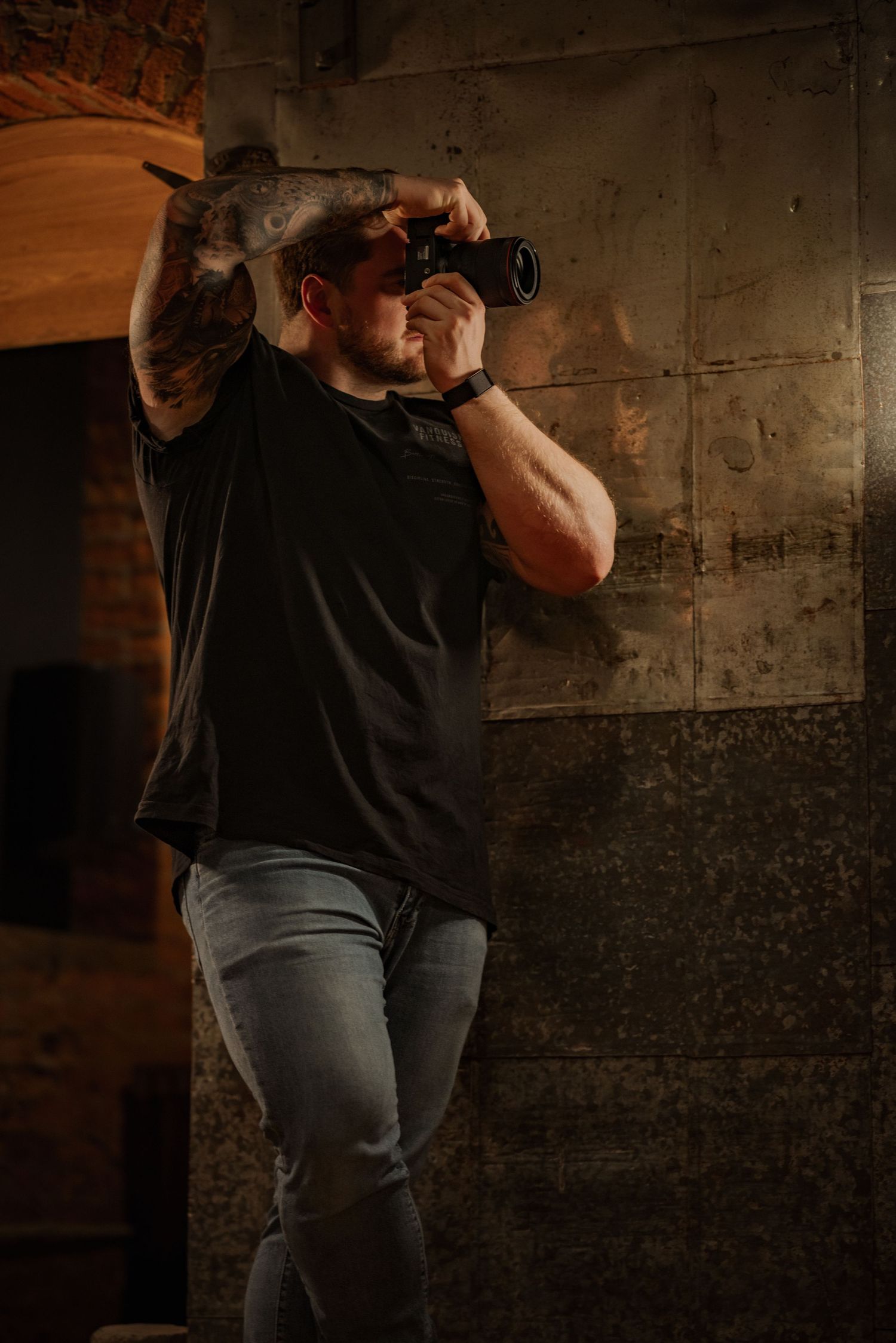 Person in black t-shirt demonstrating self-defense moves in a dimly lit industrial space.