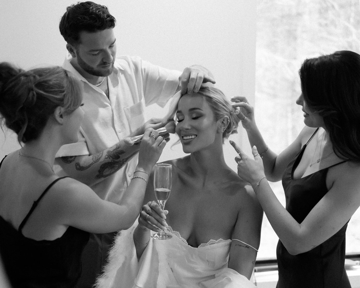 Wedding party members toasting with champagne glasses in black and white.