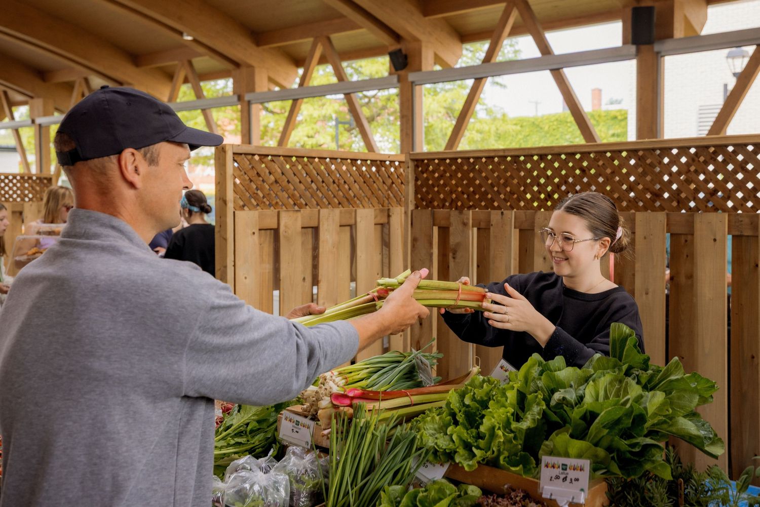 Vendors arranging fresh vegetables and produce at covered market stalls.