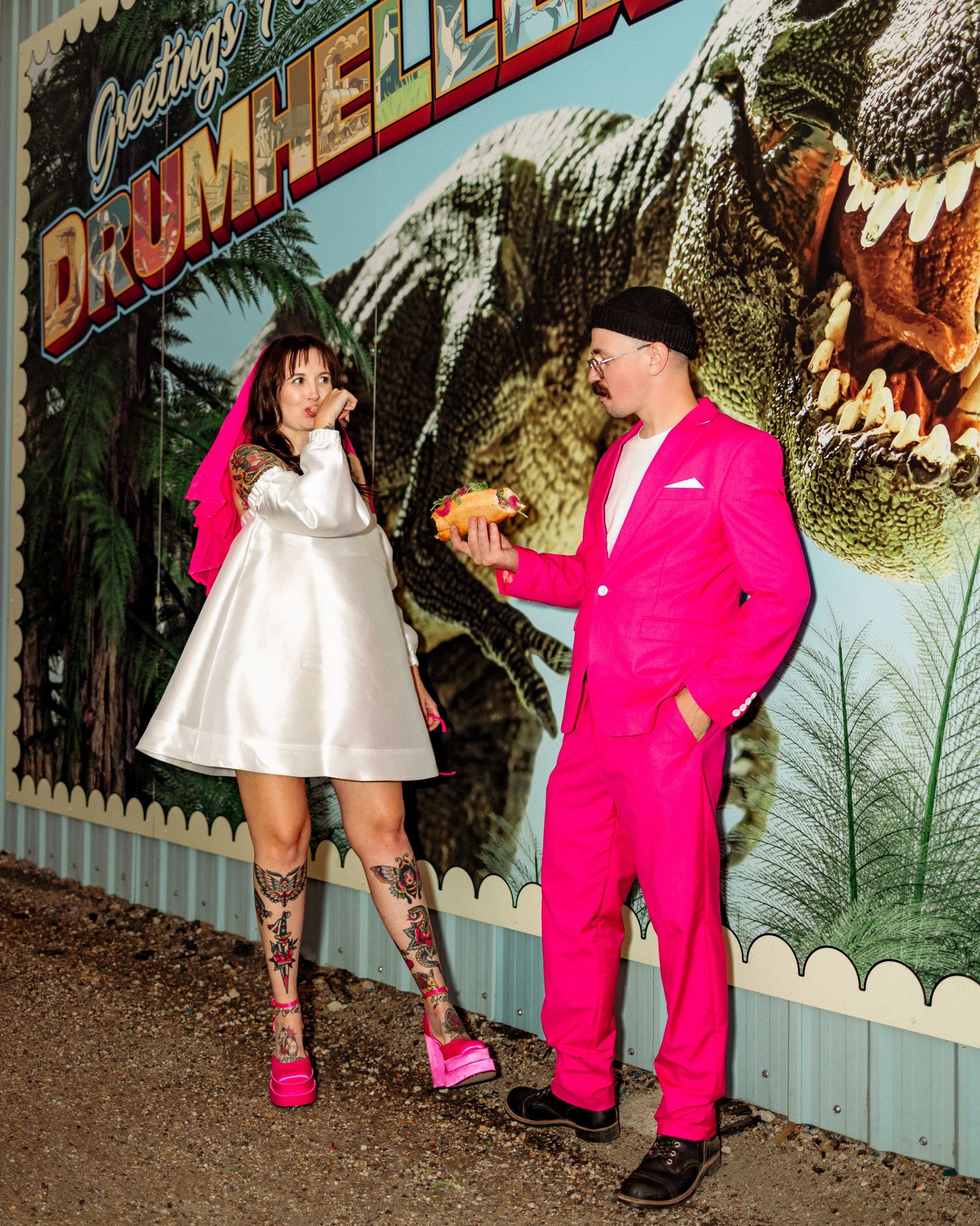 Fashion shoot against colorful dinosaur mural featuring bright pink outfits.