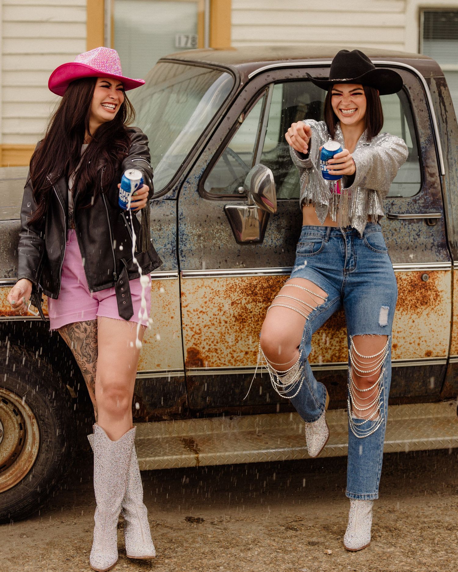 Playful western-styled shoot near a rustic car wearing cowboy boots.