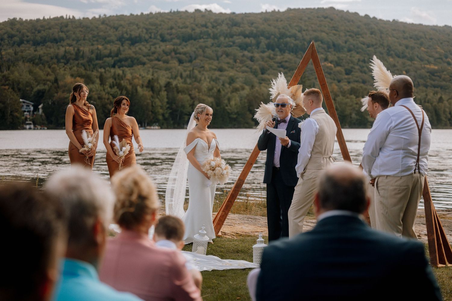 Lakeside wedding ceremony with mountain backdrop and gathered guests.