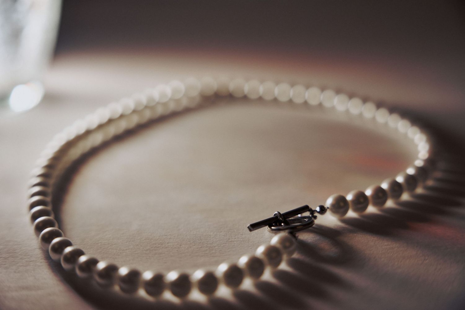 A detailed macro shot of white pearl jewelry on a dark wooden surface.