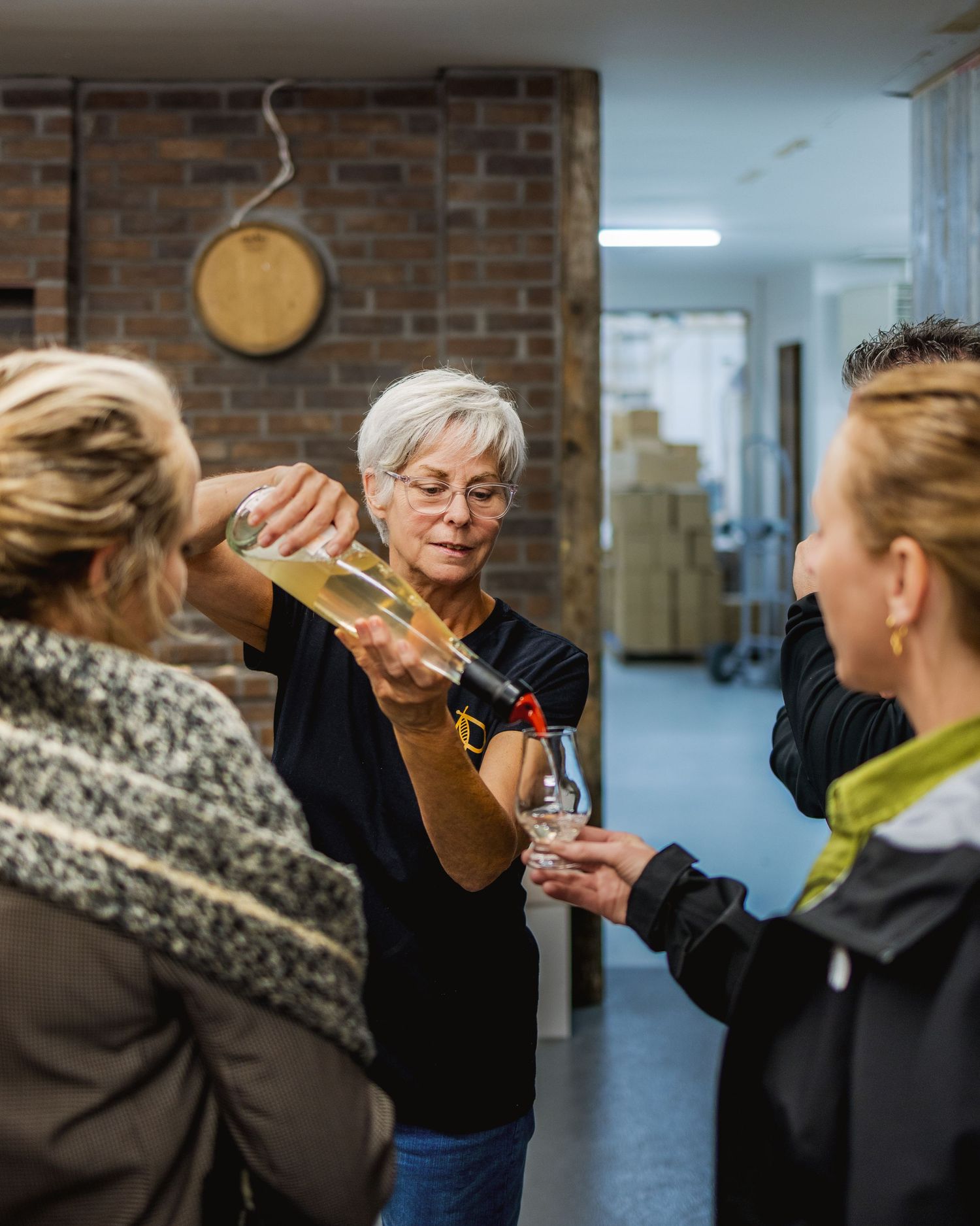 Group participating in spirit tasting session in brick-walled space.